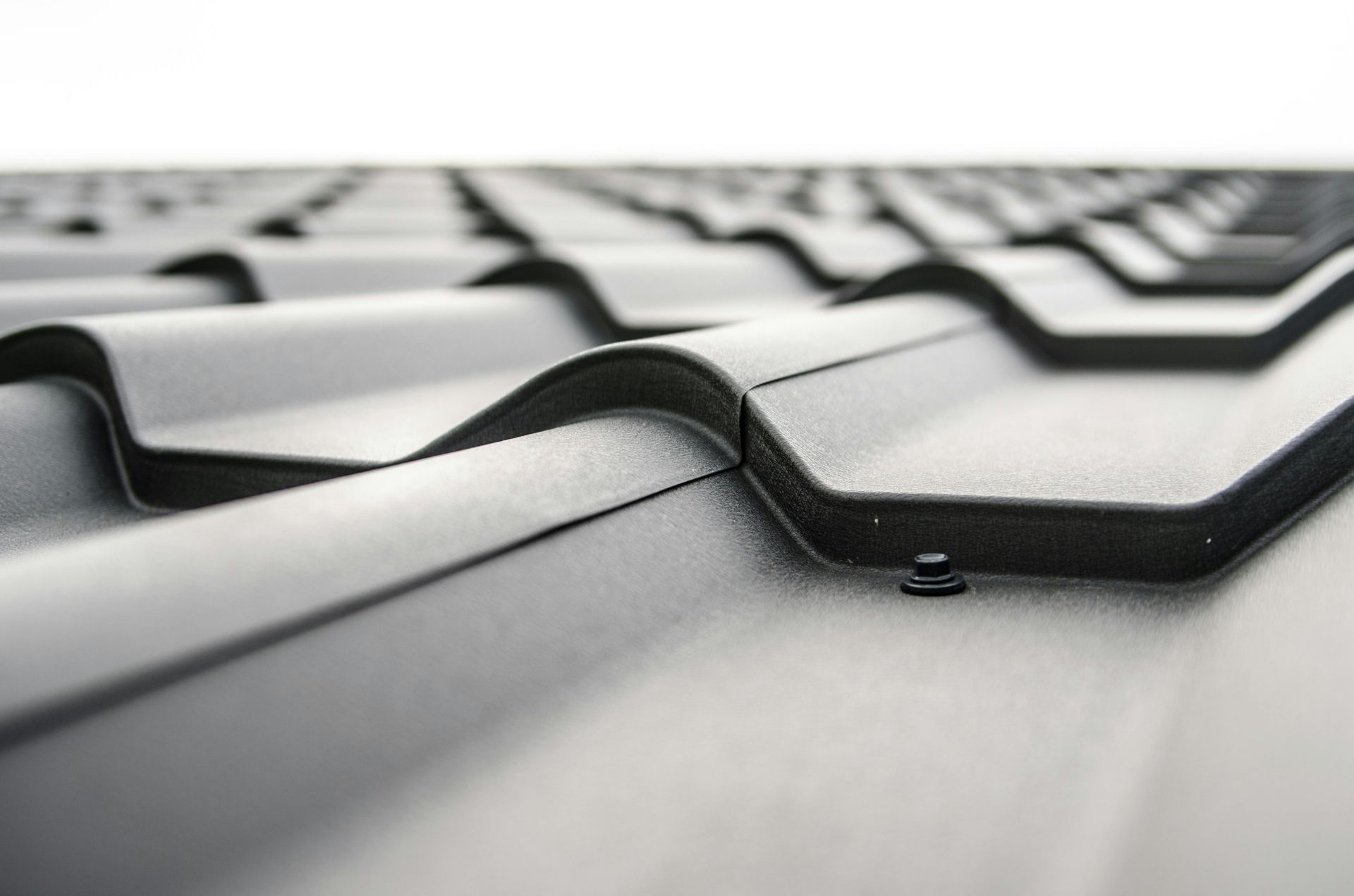 Close-up of gray corrugated roof panels with black trim in soft focus