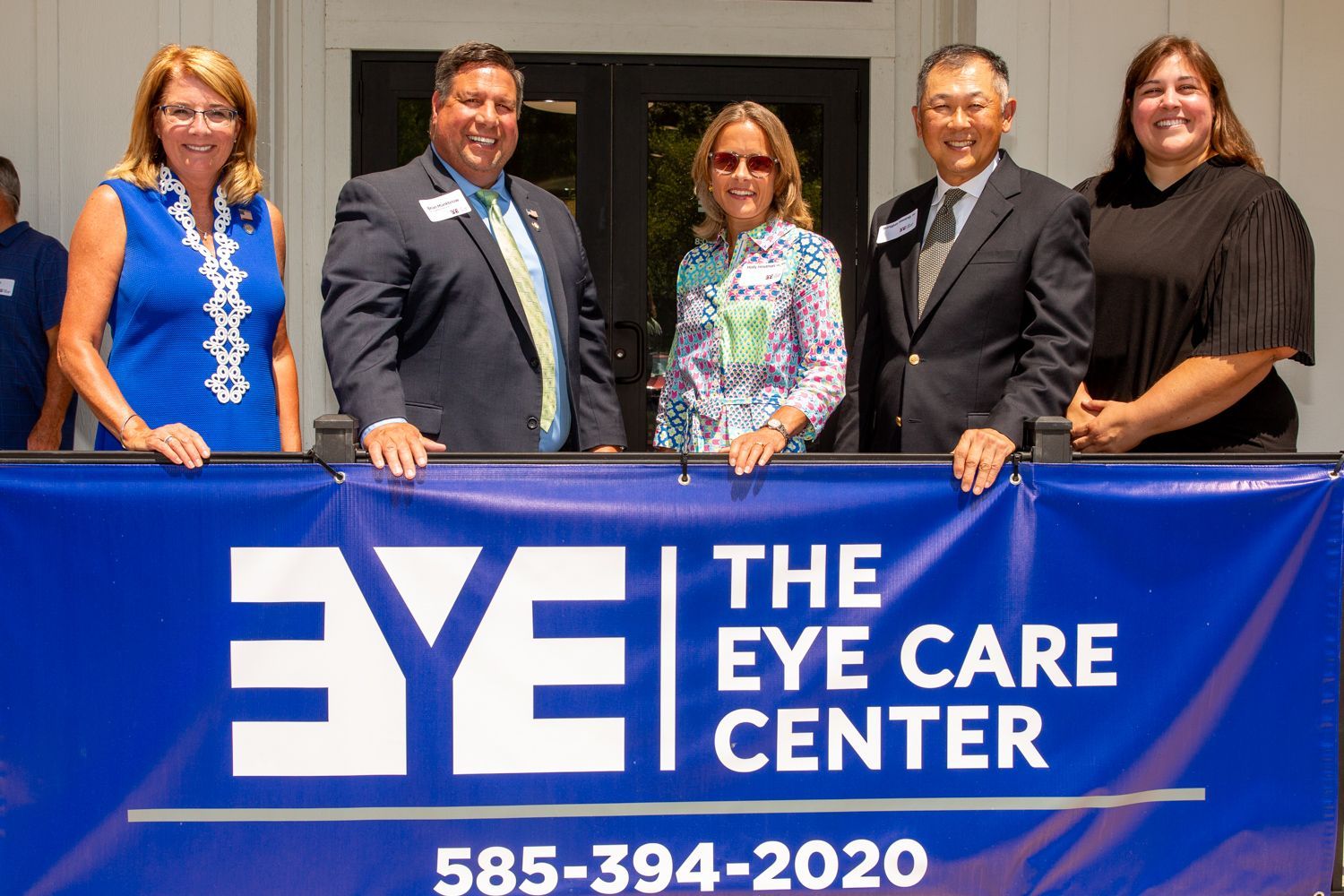 people standing behind the banner for The Eye Care Center outside the building