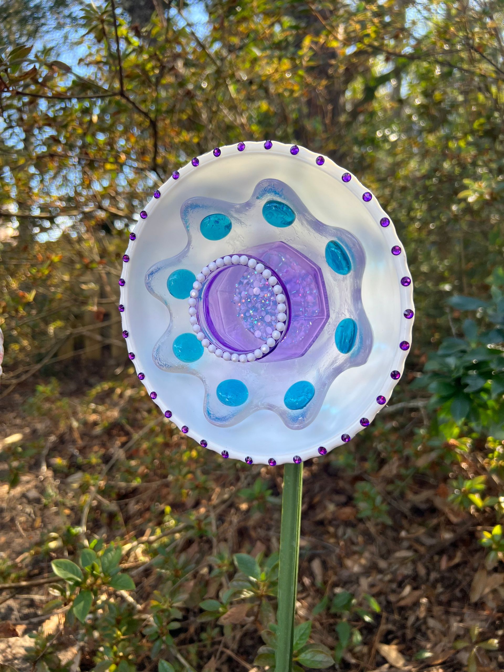 Hands decorating a Christmas wreath with dried fruit and greenery on a wooden table.