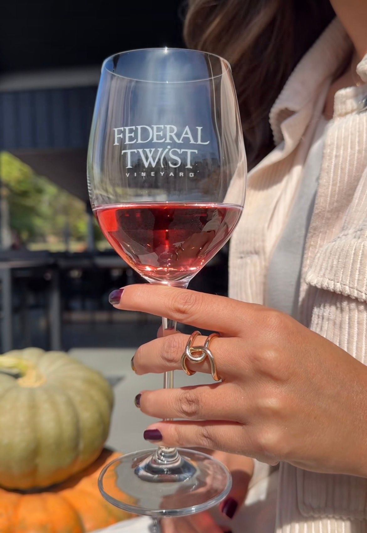 A glass of rosé wine and a vase of peach-colored flowers.