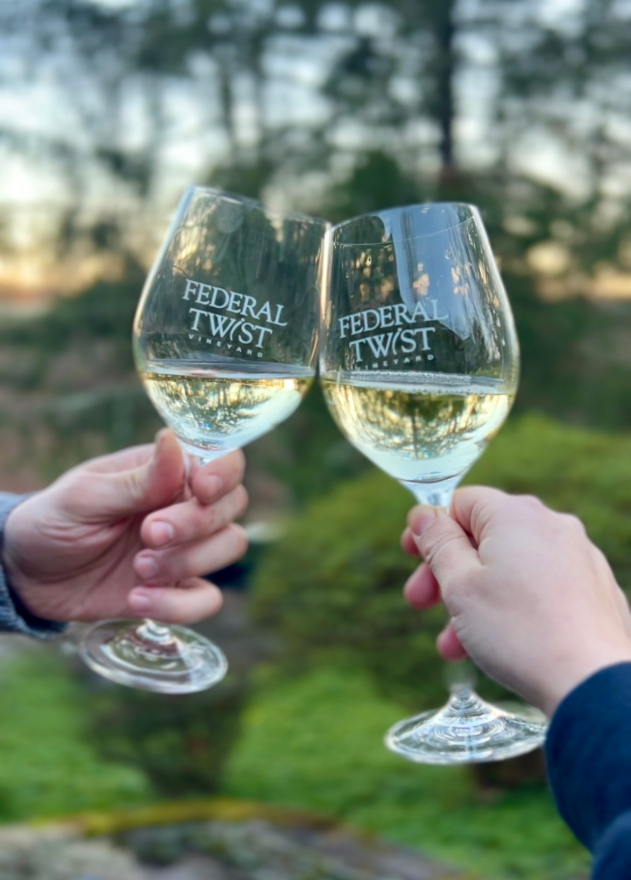 Hands decorating a Christmas wreath with dried fruit and greenery on a wooden table.
