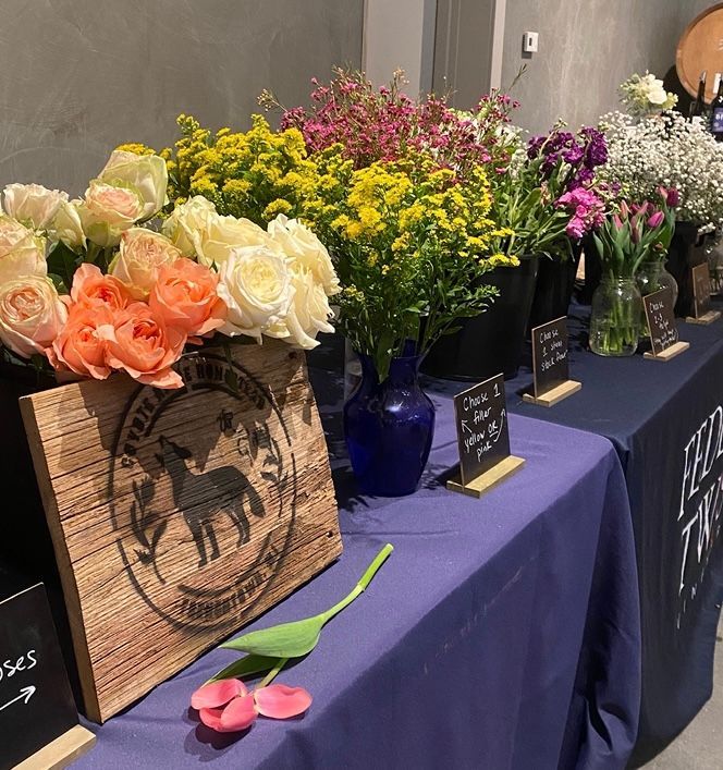 Hands decorating a Christmas wreath with dried fruit and greenery on a wooden table.