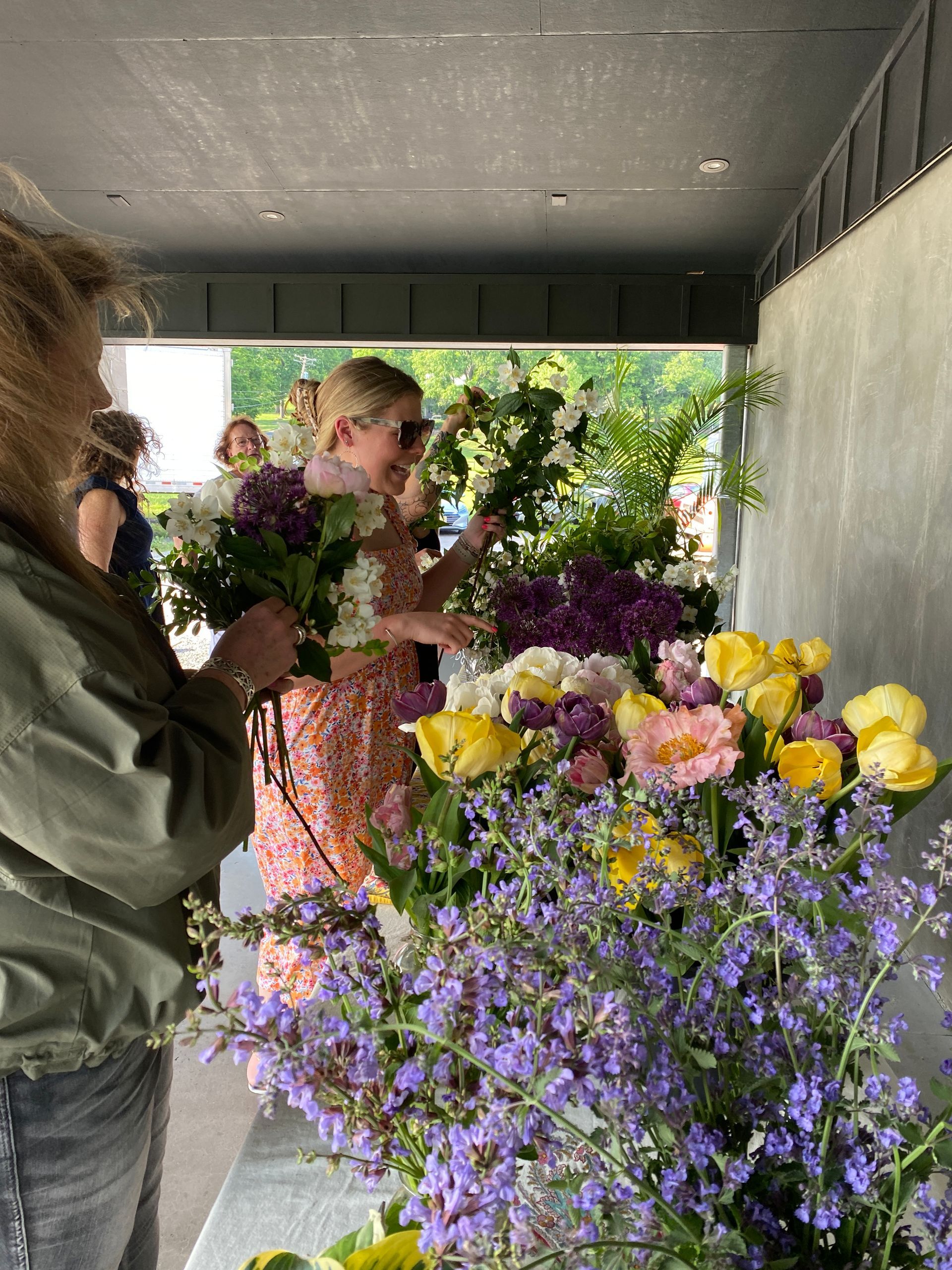 Hands decorating a Christmas wreath with dried fruit and greenery on a wooden table.