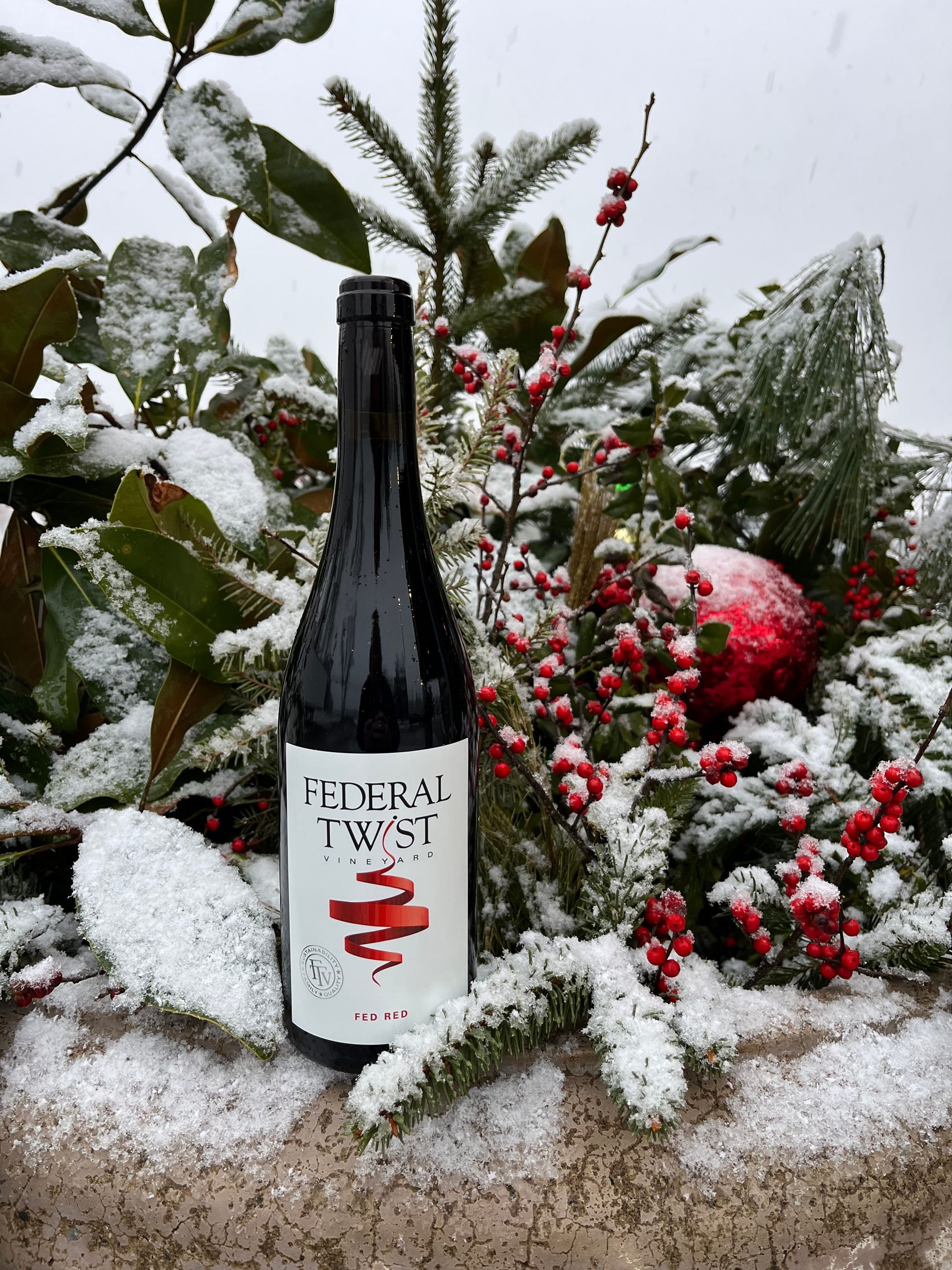 Hands decorating a Christmas wreath with dried fruit and greenery on a wooden table.