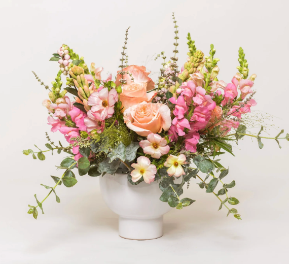 Hands decorating a Christmas wreath with dried fruit and greenery on a wooden table.