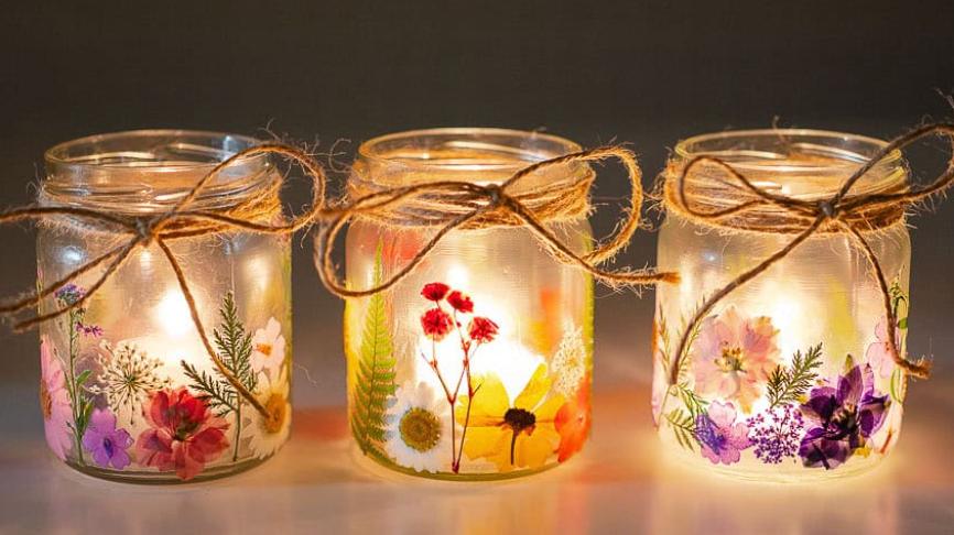 Hands decorating a Christmas wreath with dried fruit and greenery on a wooden table.