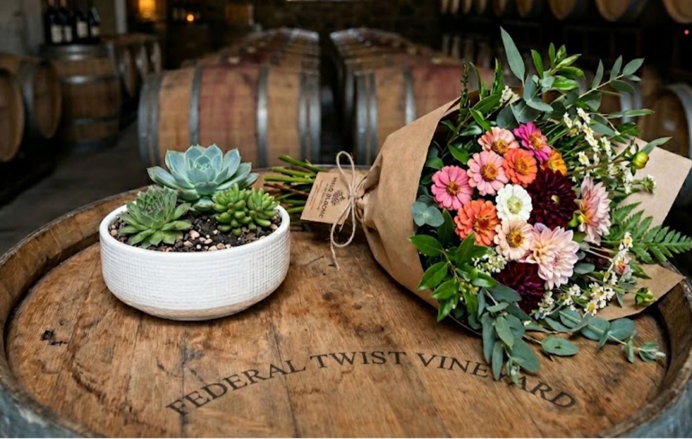 Hands decorating a Christmas wreath with dried fruit and greenery on a wooden table.