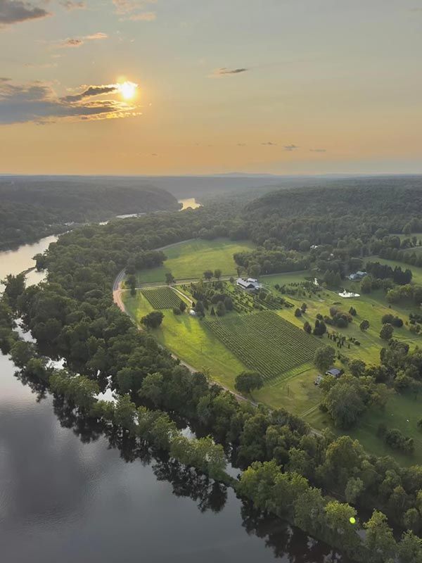 River valley at sunset; sunlight over fields, trees, and winding river.