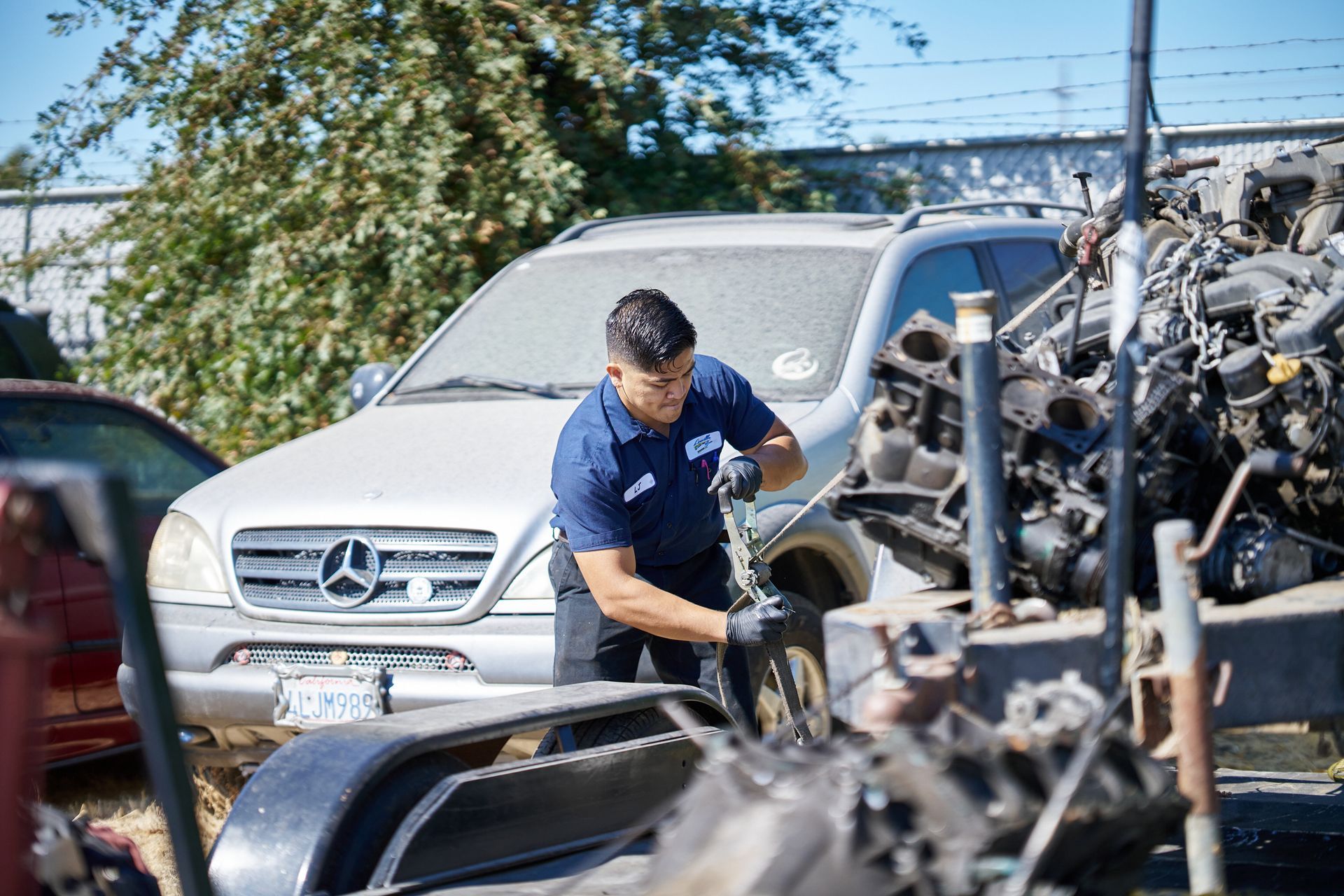 Man in a junkyard working on a tire next to a silver car | Linville Brothers