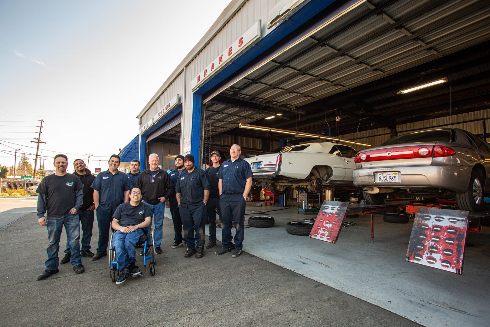 Auto Repair Team Standing Outside Garage With Cars On Lifts | Linville Brothers