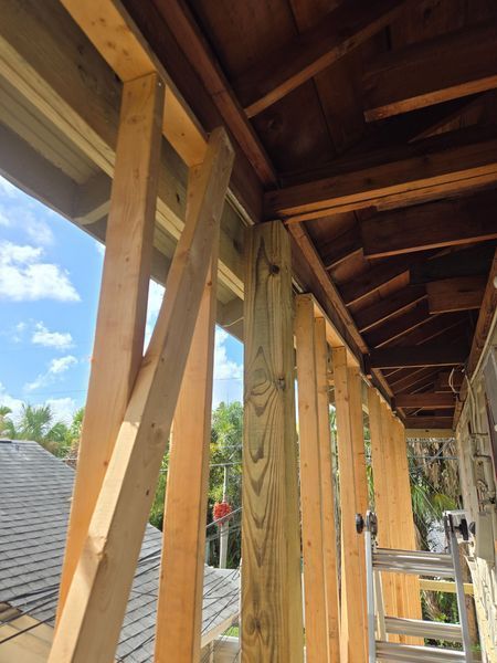 Wooden porch framing being built. Support beams with bracing against a blue sky background.