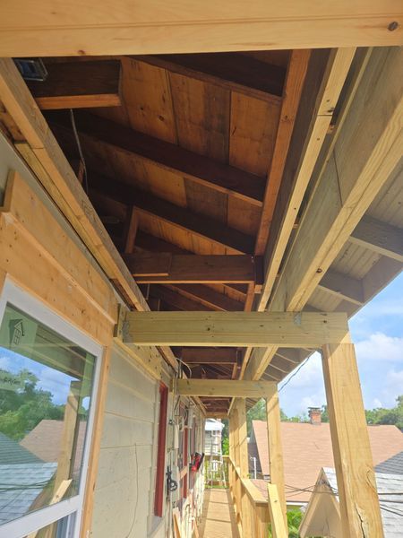 Exterior porch under construction with wood beams and planks; view looking up.