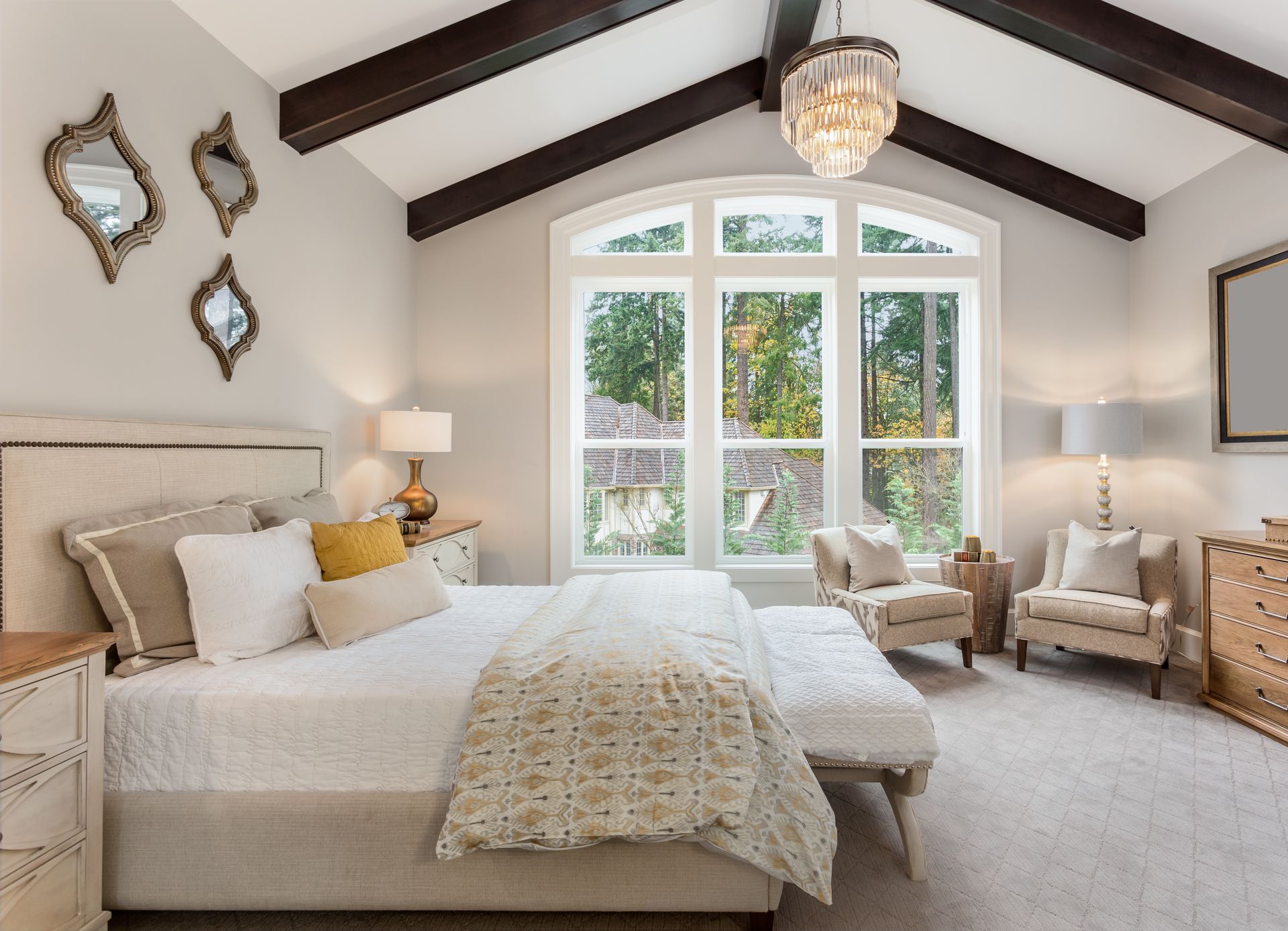 Bedroom with white bed, arched window, and decorative mirrors.