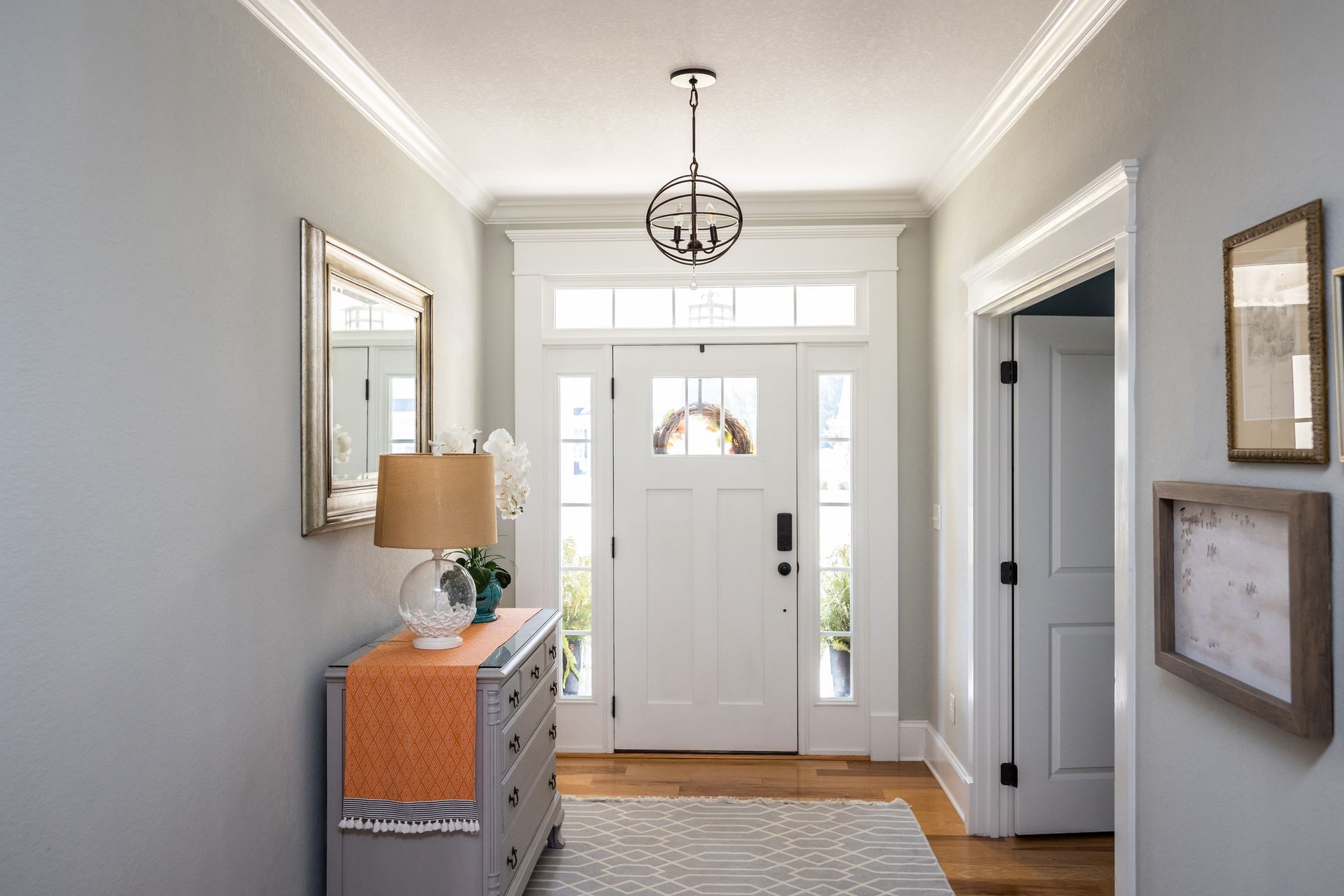 Entryway with white door, gray walls, wooden floor, and a dresser with decor.