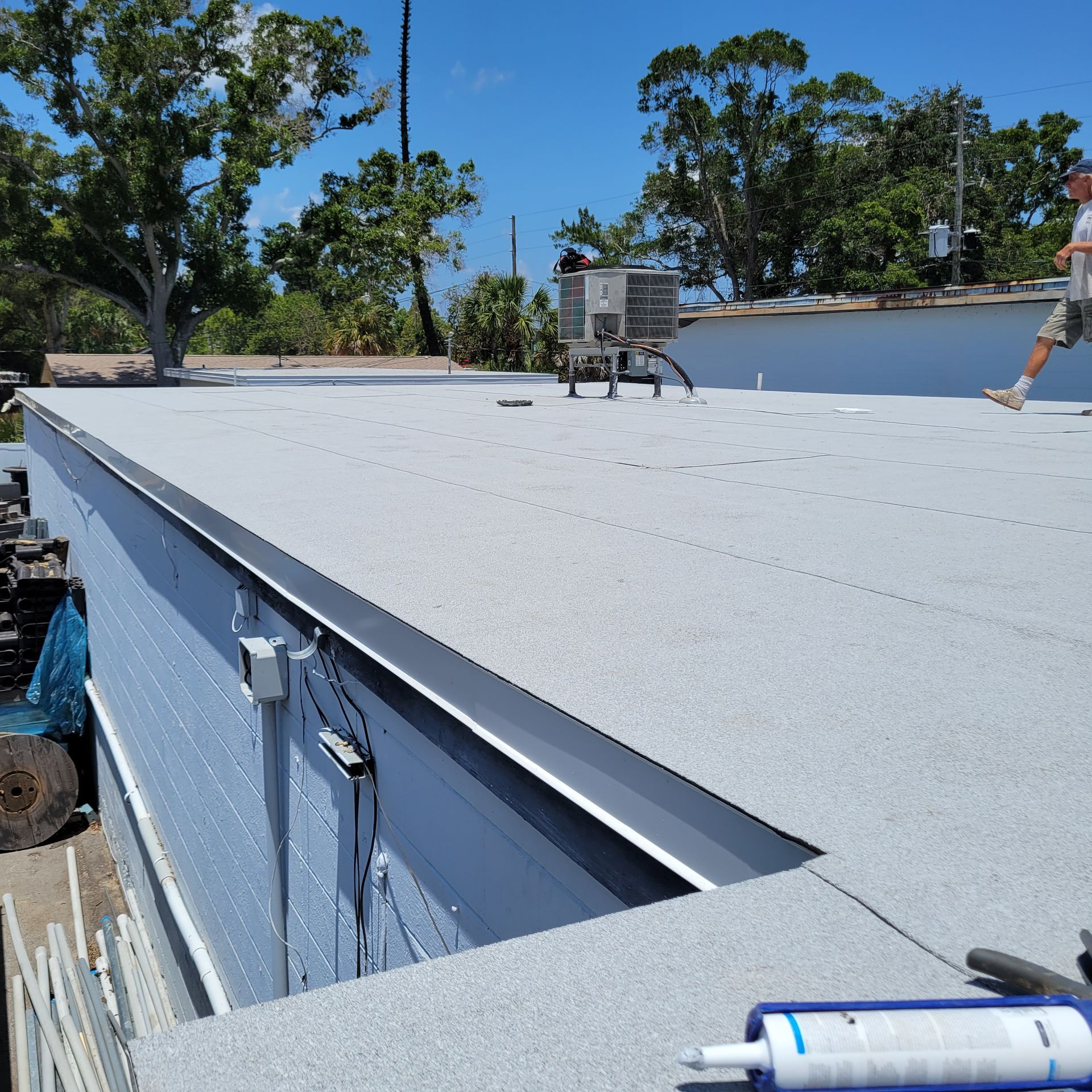Hammer, nails, and orange work glove on black roofing shingles.