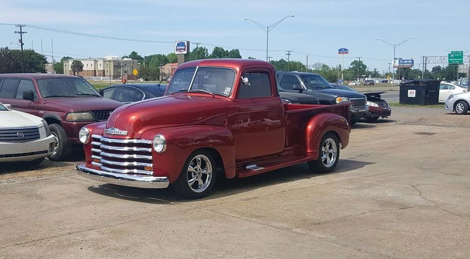 a red chevrolet truck is parked in a parking lot