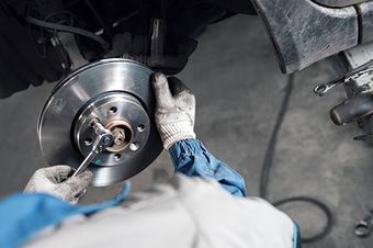 a mechanic is fixing a brake disc on a car with a wrench .