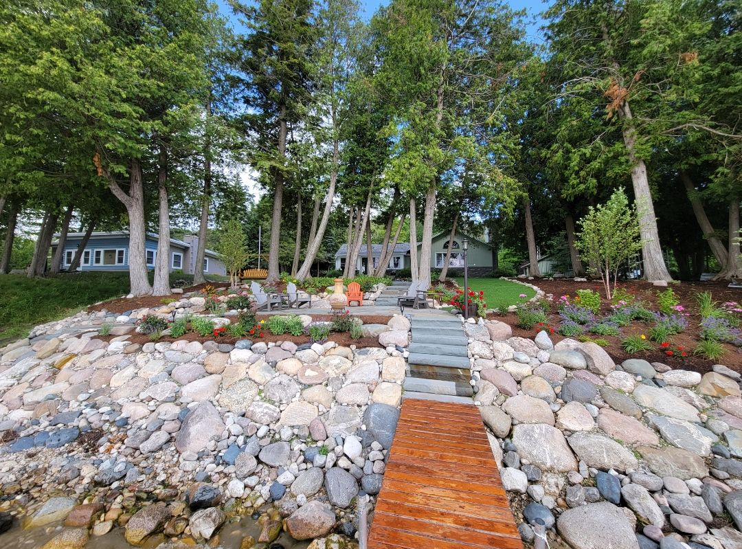 Three distinct textures—crushed grey stone, smooth river rocks, and green synthetic turf—divided by metal edging strips.