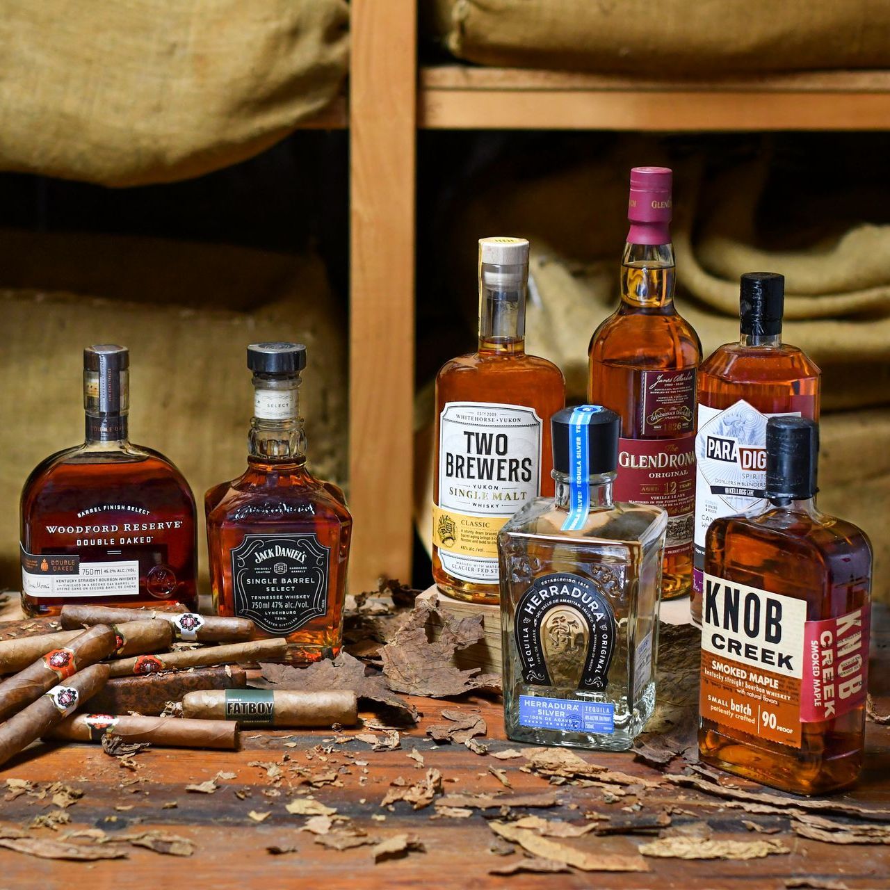 A table topped with bottles of whiskey and cigars.