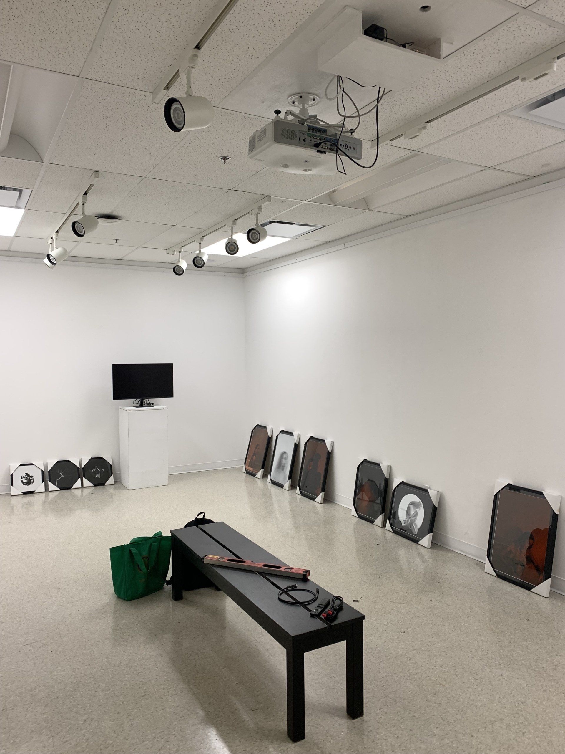 A room with a bench, picutre frames on the phone, and a tv on the wall.