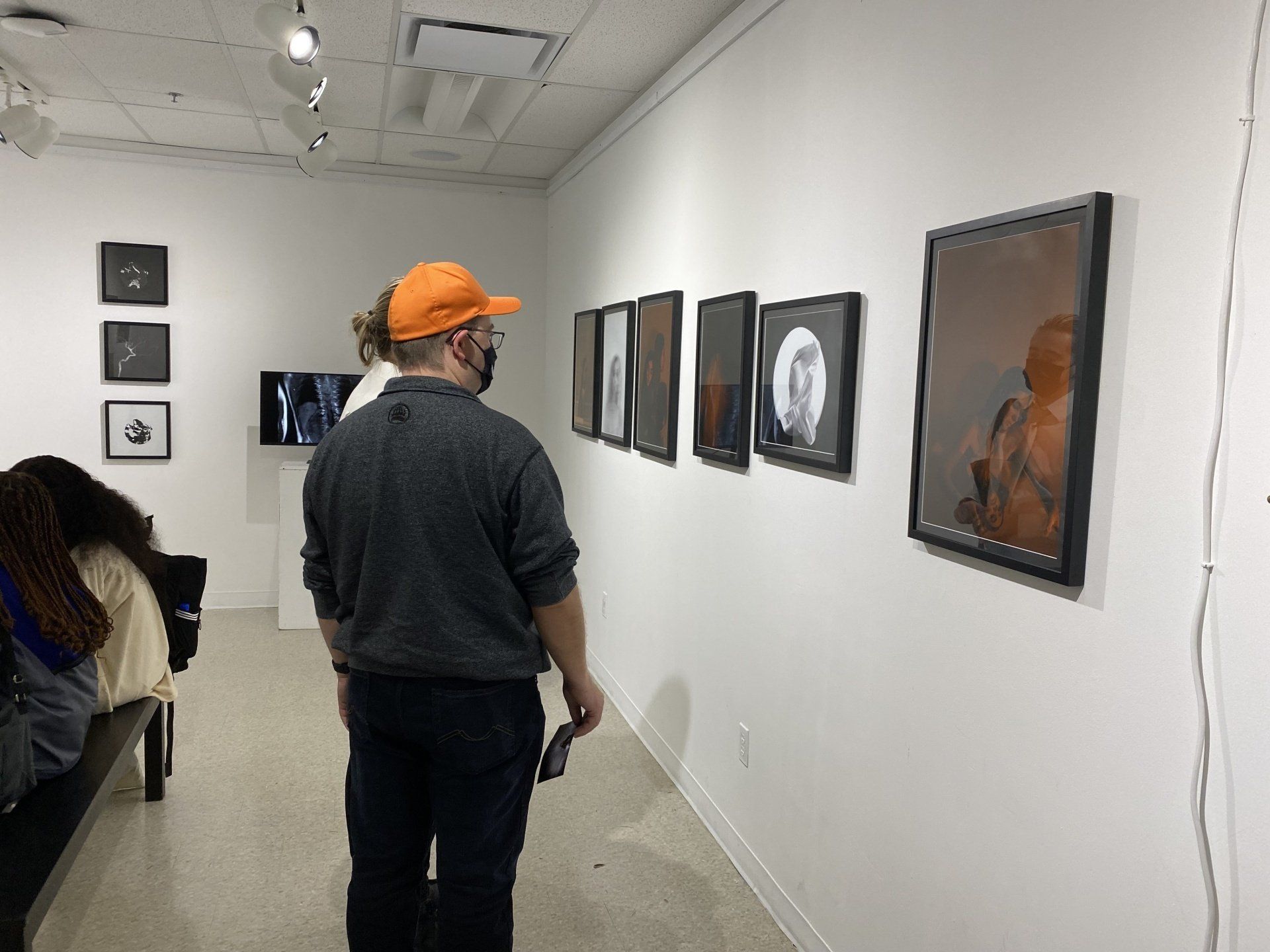 People are looking at picutres on a wall.