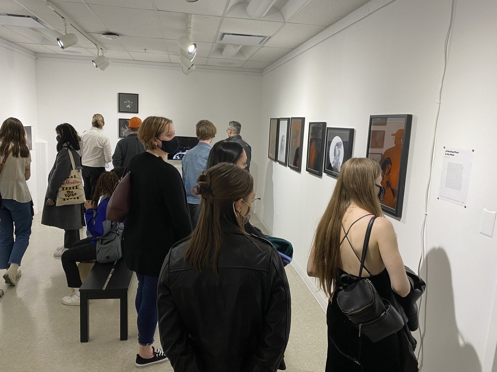 A group of people are looking at pictures on a wall.