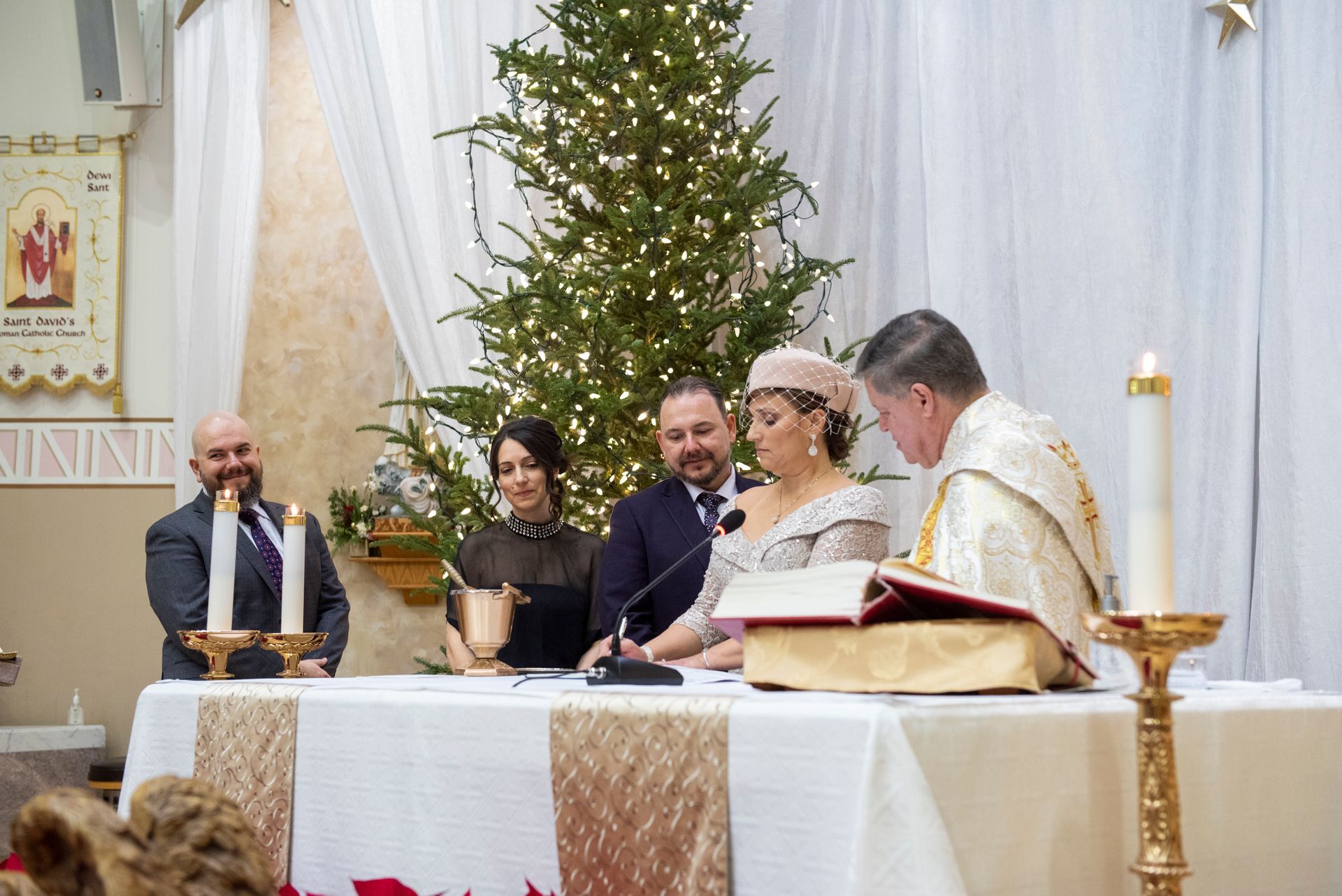 Wedding ceremony in a church with couple, priest, and attendees at a decorated altar.