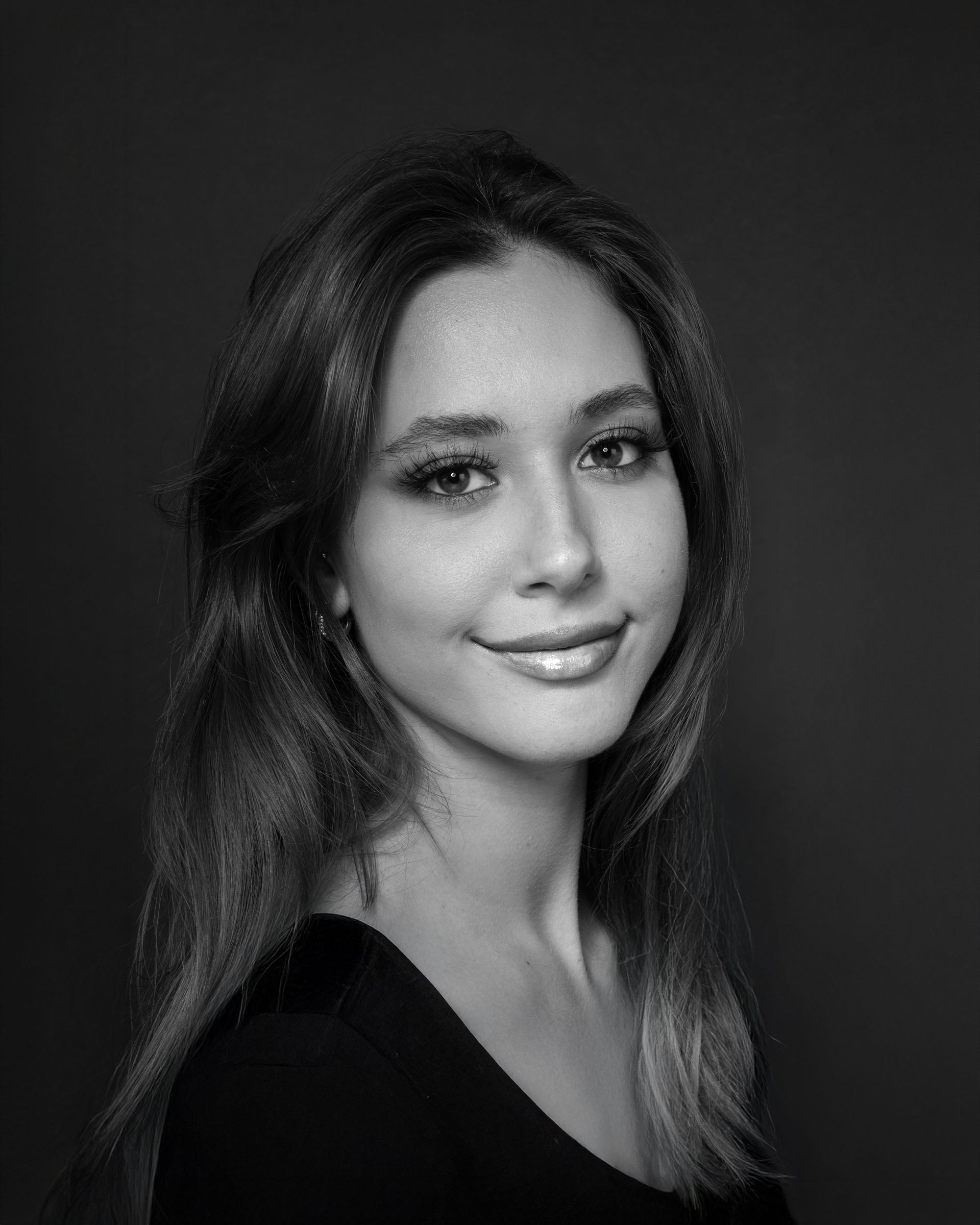 Woman with long hair smiles, posing for a portrait. Black and white photo.