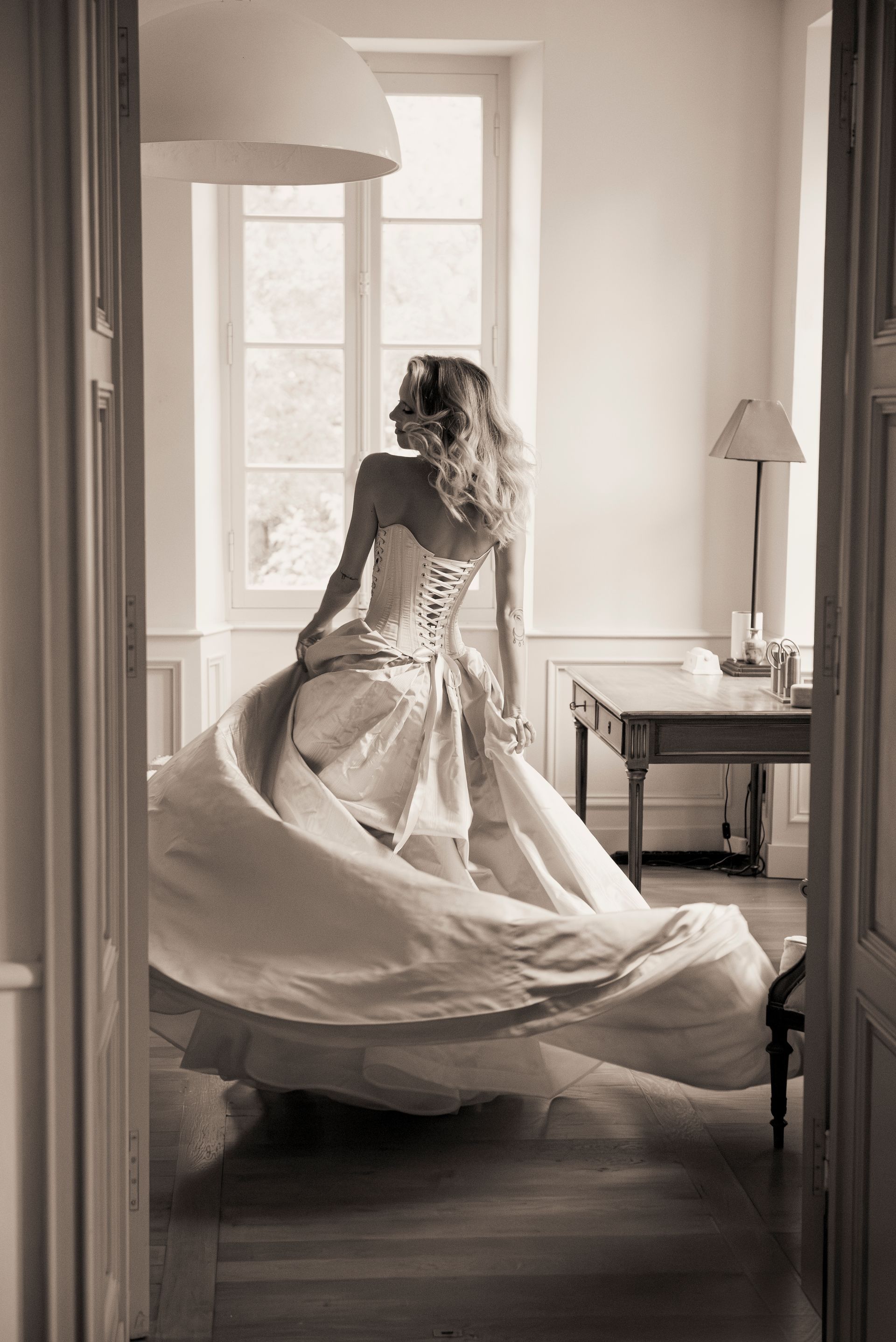 Woman in flowing gown, twirling in front of a bright window. Sepia tones.