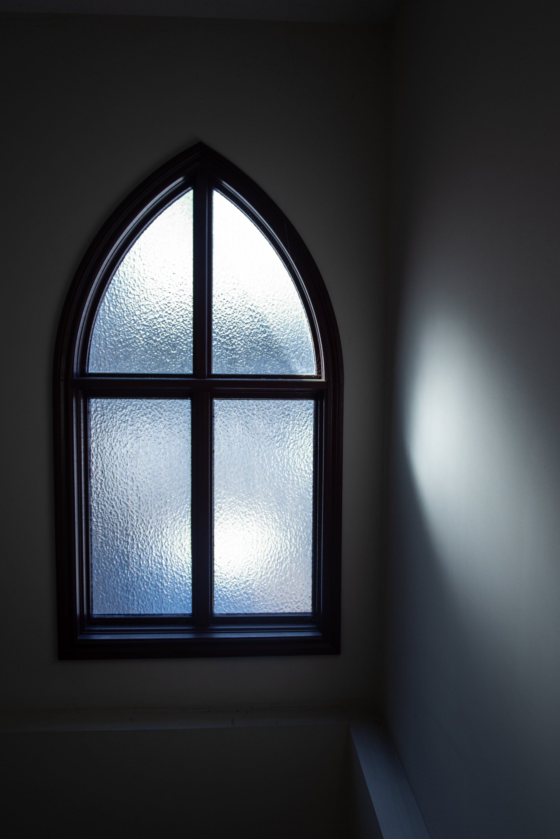 A window in a dark room with a light coming through it