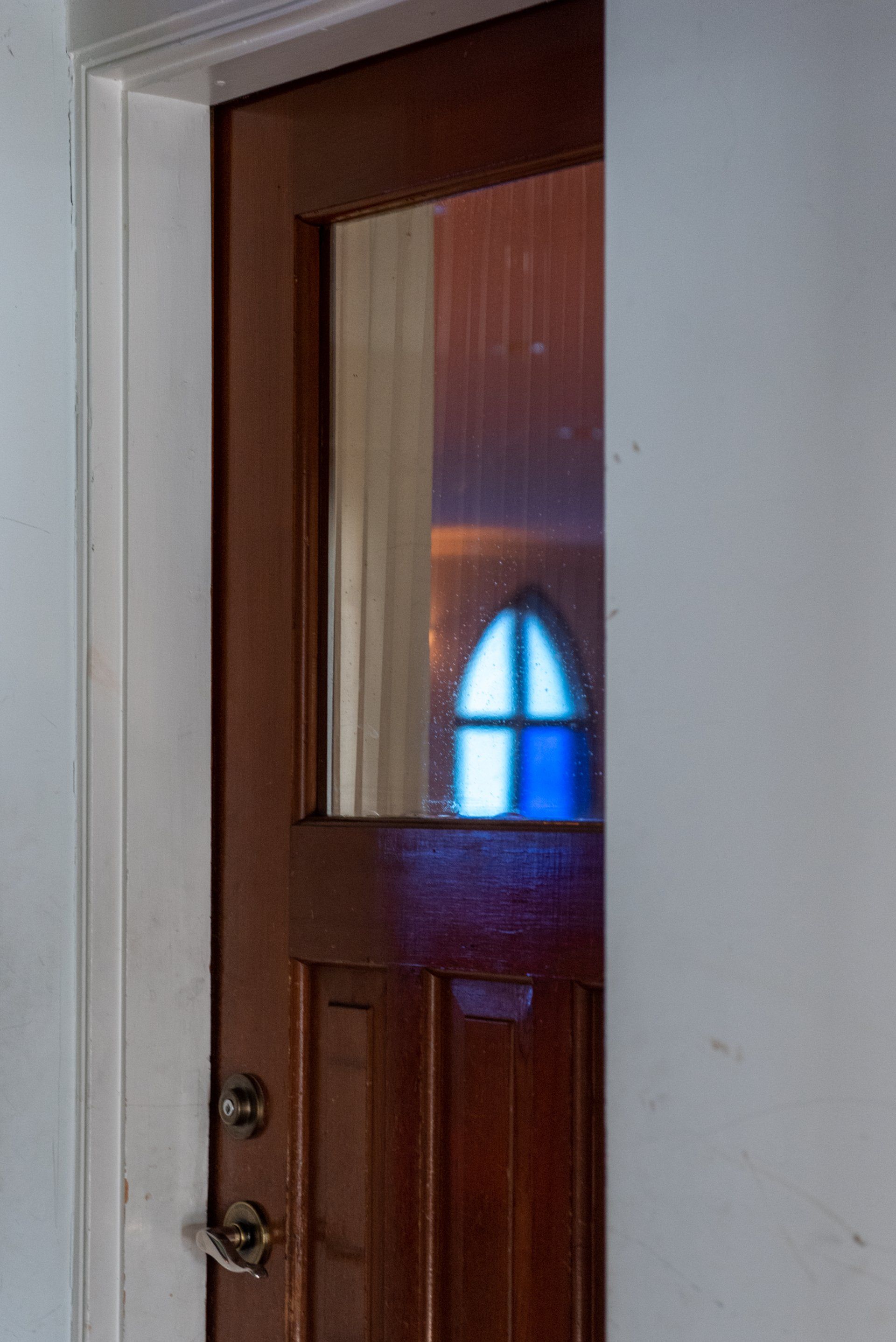 A door with a window in it and a reflection of a stained glass window.