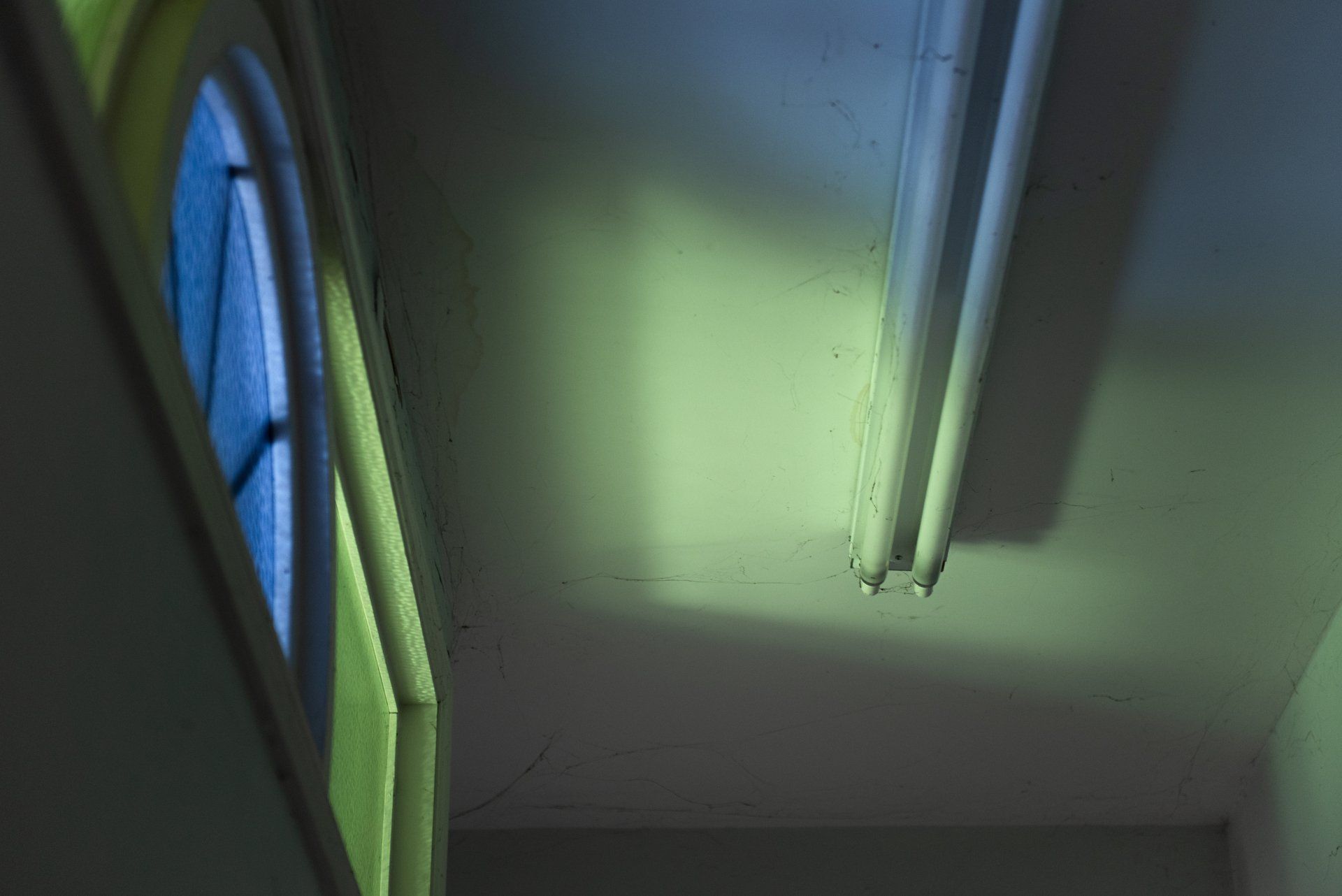 A hallway with a stained glass window and a light on the ceiling.