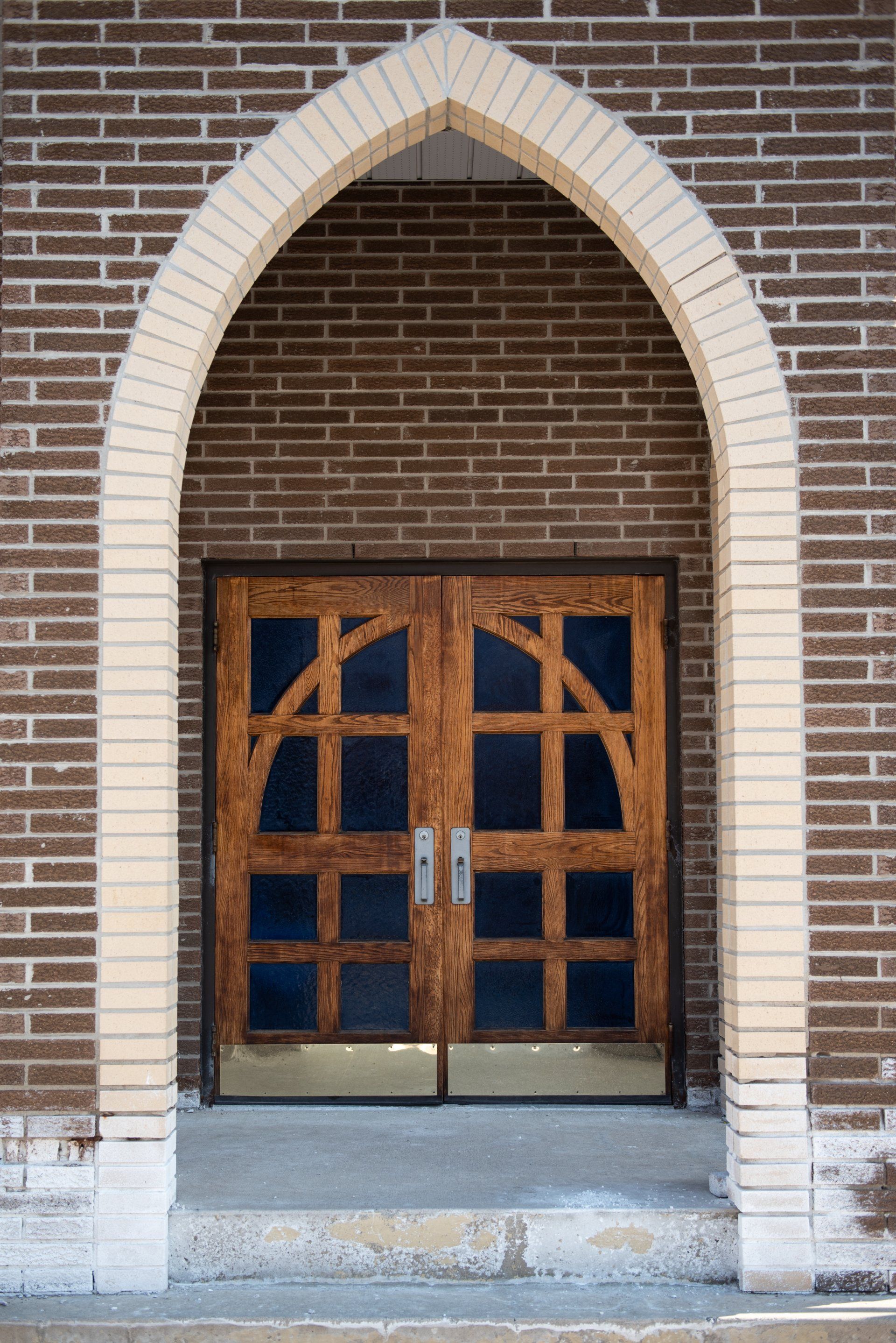 A brick building with a wooden door and stained glass windows.