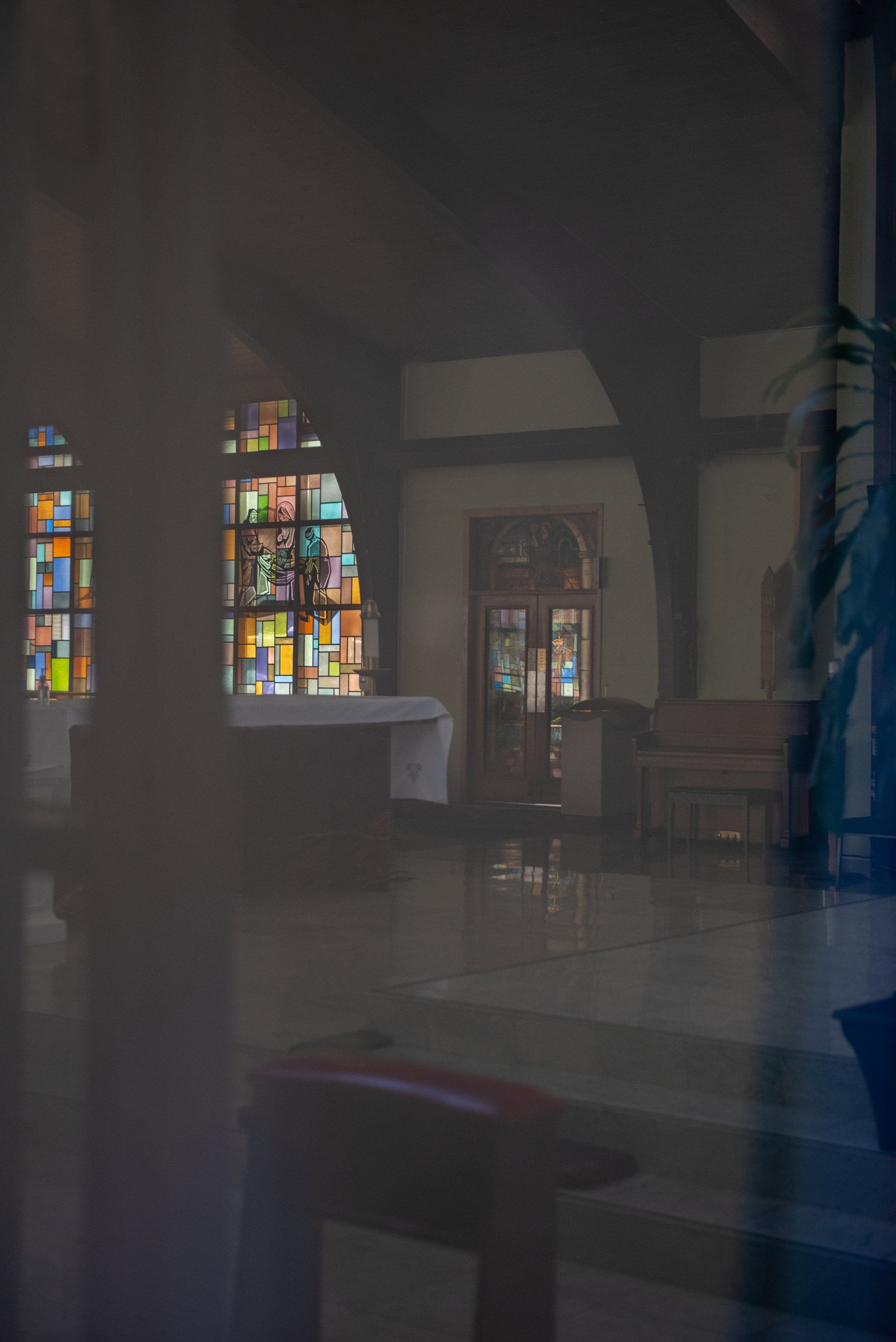 A stained glass window in a church is visible through a window.