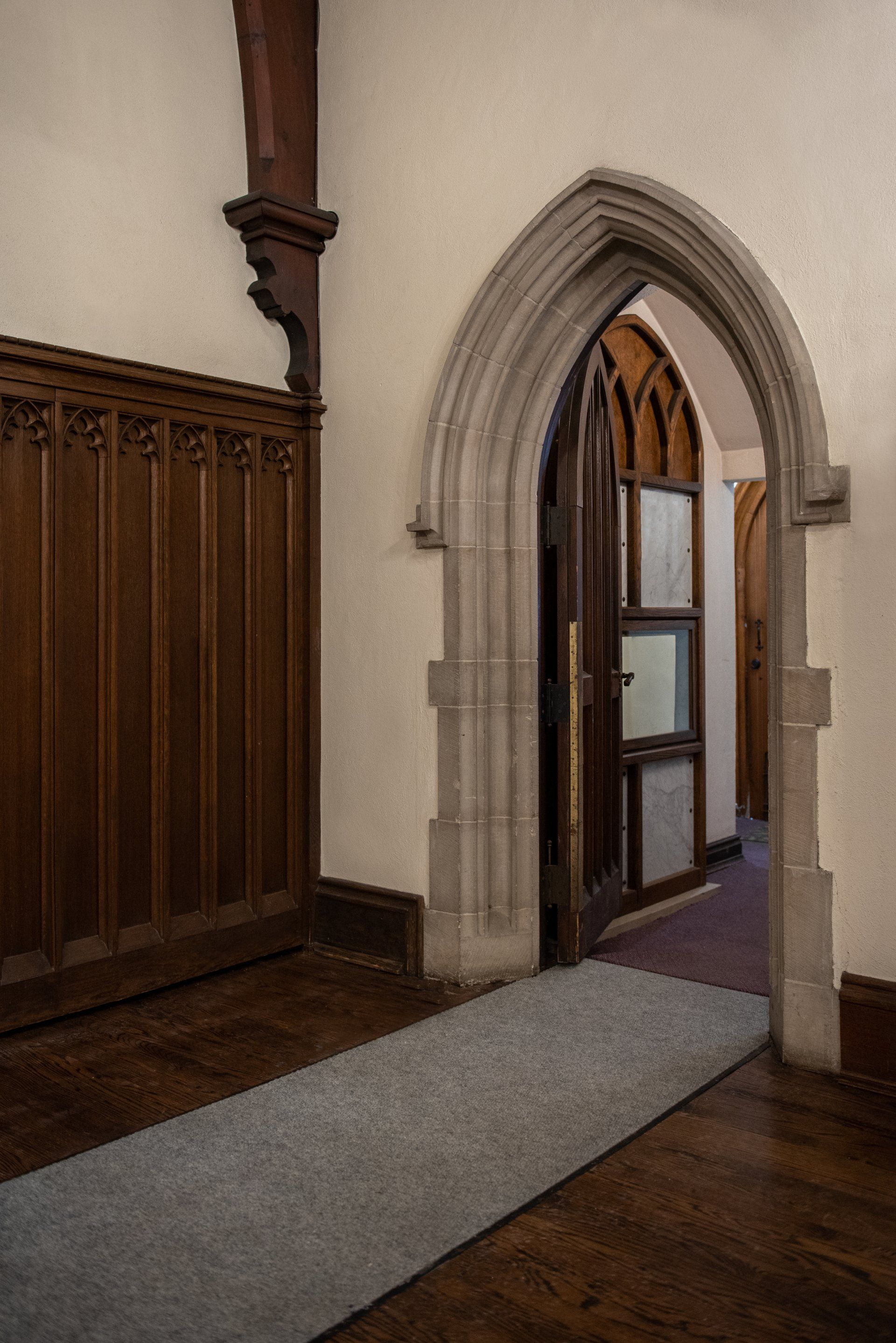 A hallway with a stone archway leading to a door.