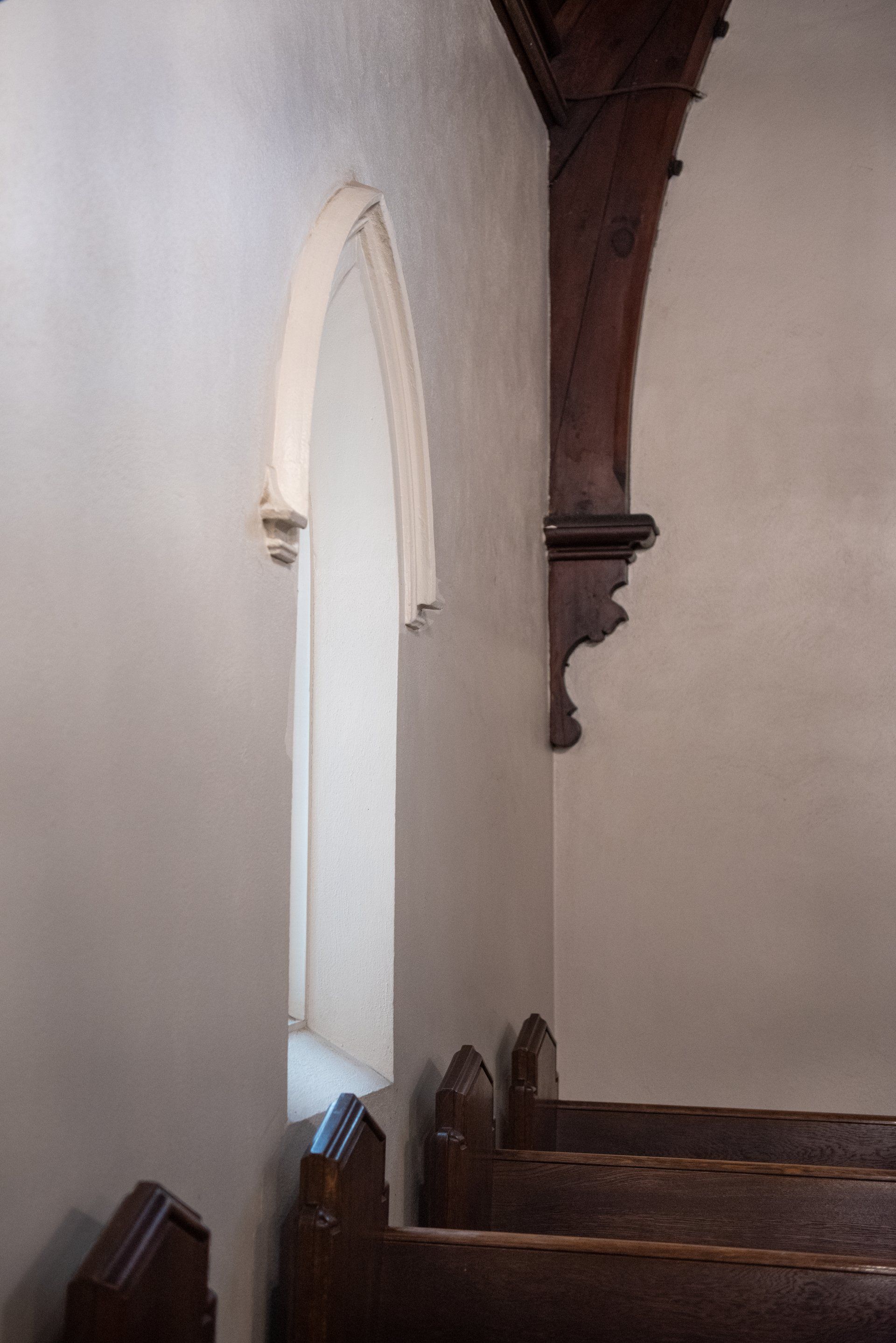 The inside of a church with a window and benches.