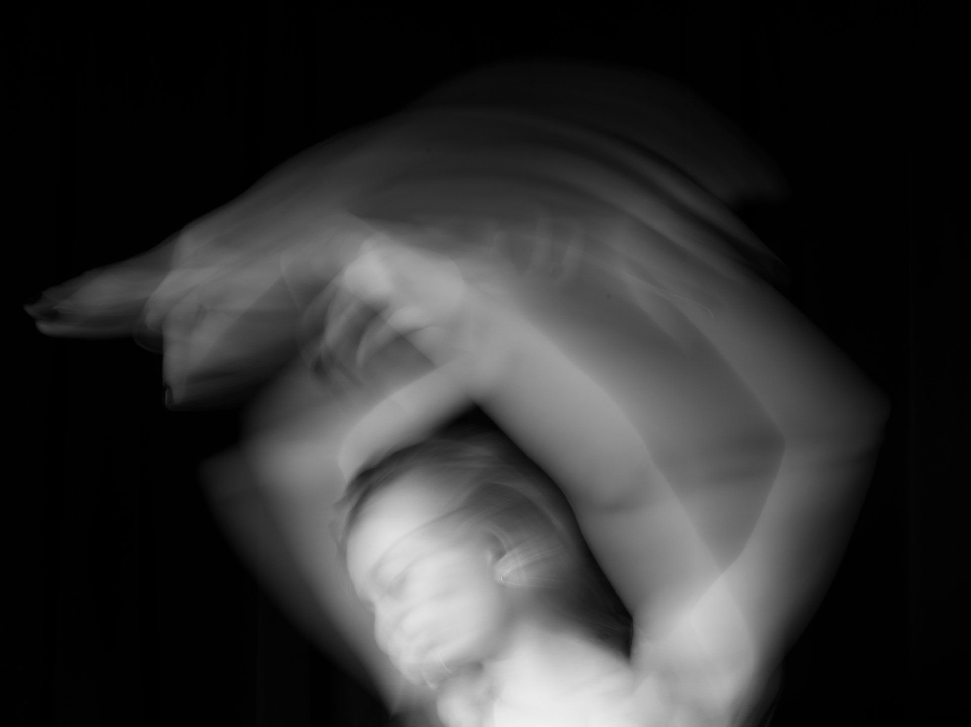 A blurry black and white photo of a woman dancing in the dark.