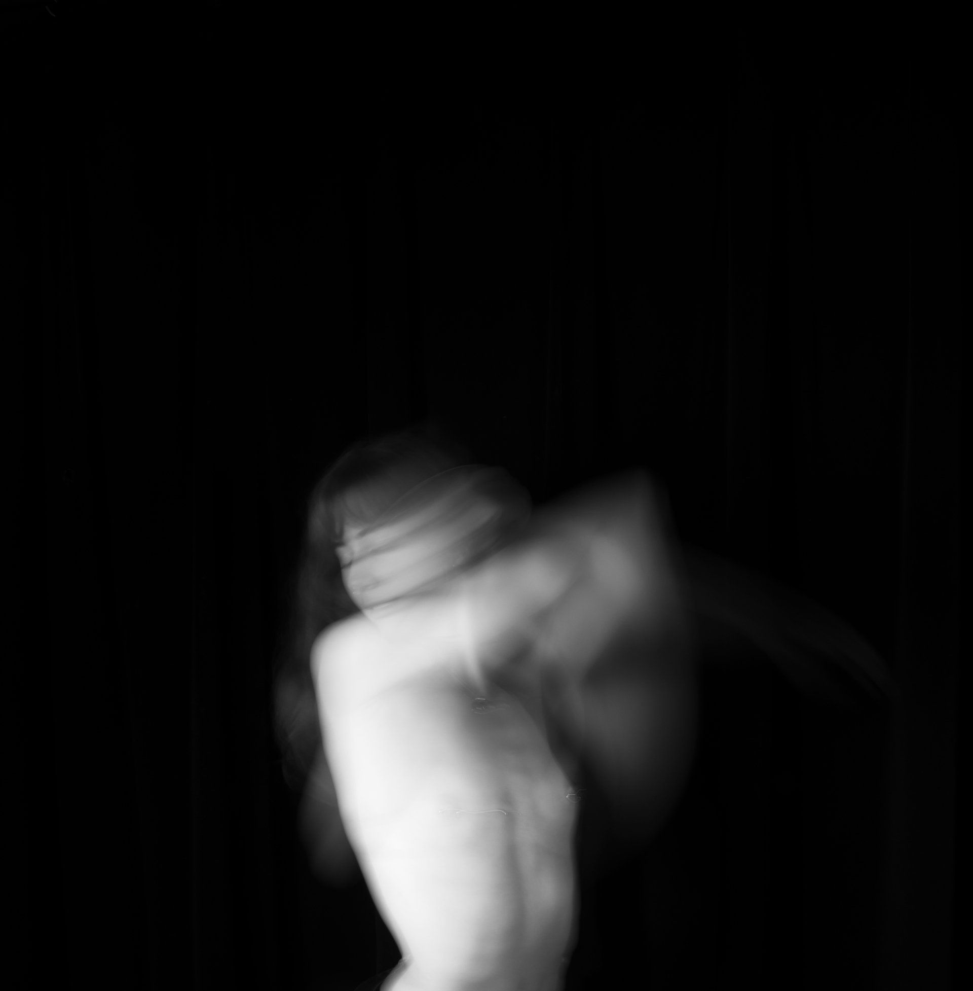 A blurry black and white photo of a woman dancing in the dark.