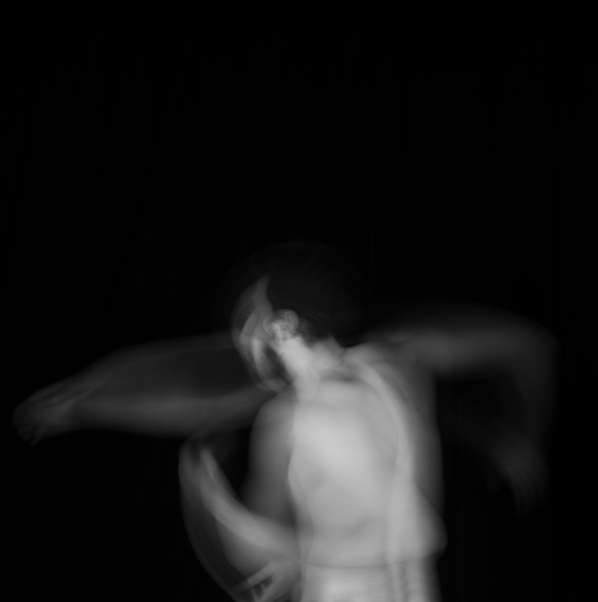 A blurry black and white photo of a man dancing in the dark.