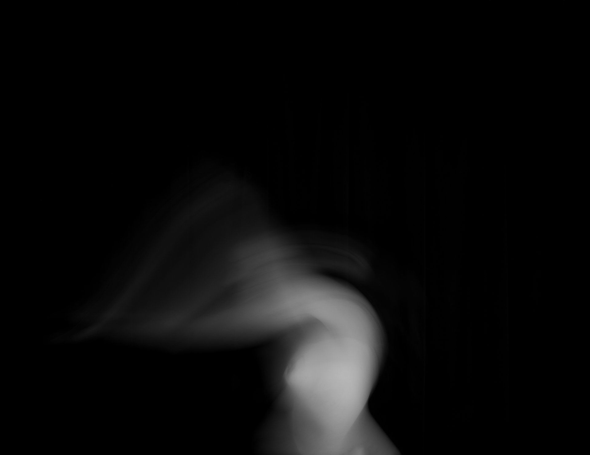 A blurry black and white photo of a woman dancing in the dark.