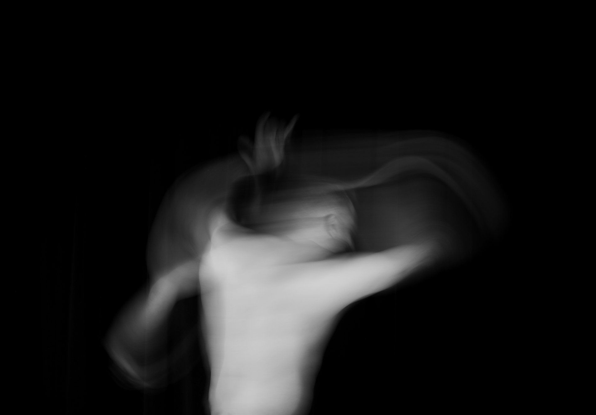 A blurry black and white photo of a man dancing in the dark.