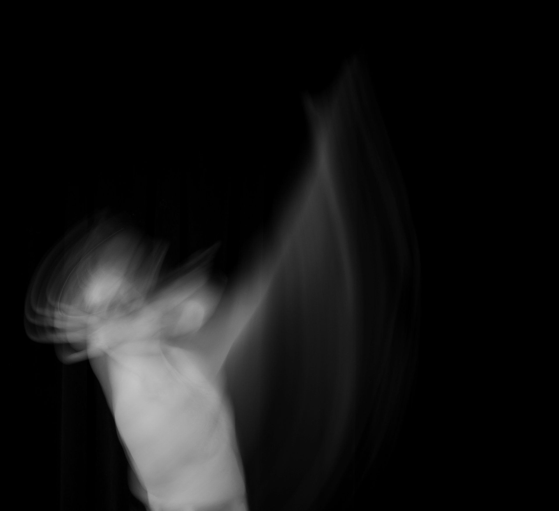 A blurry black and white photo of a man dancing in the dark.