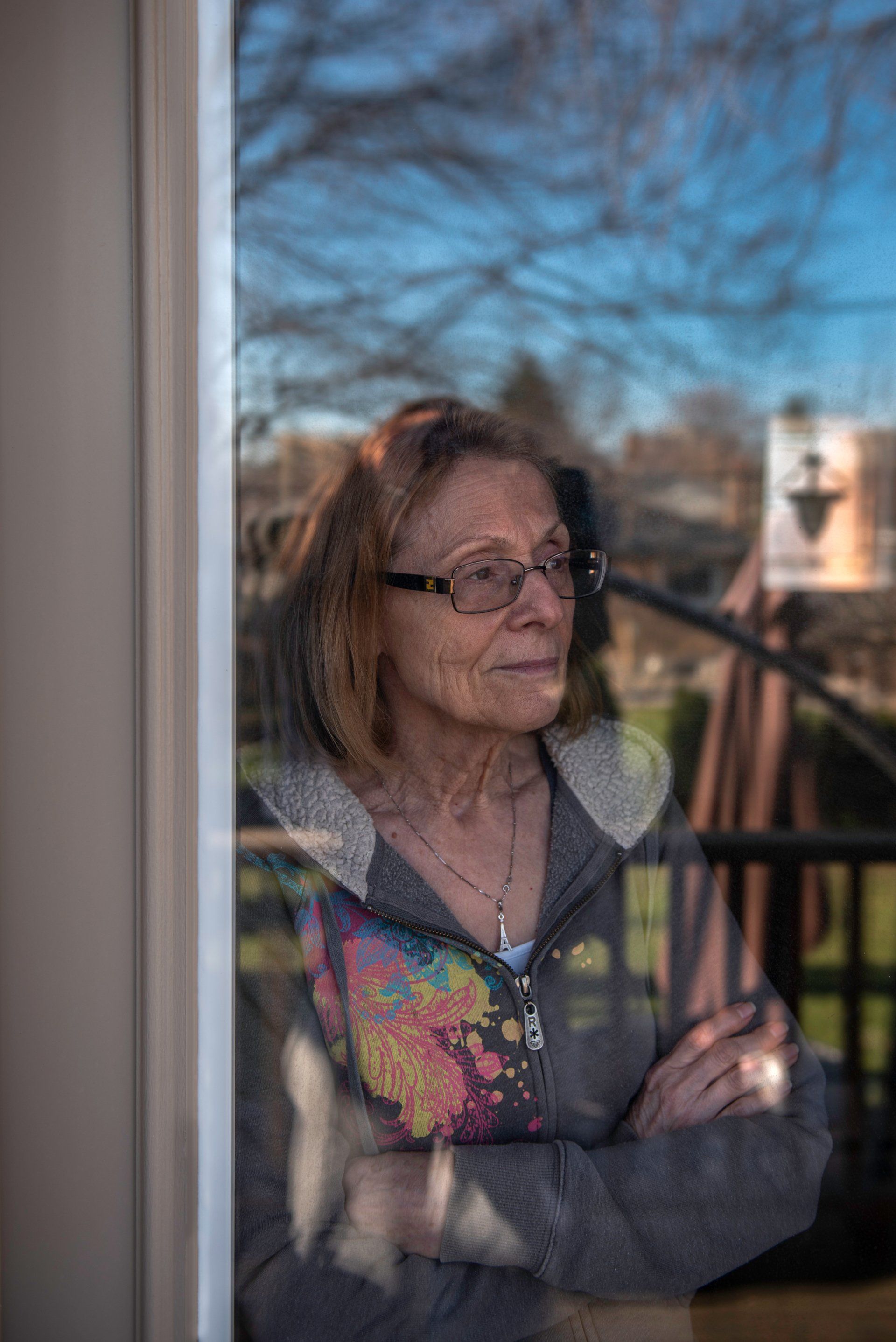 An elderly woman is looking out of a window.