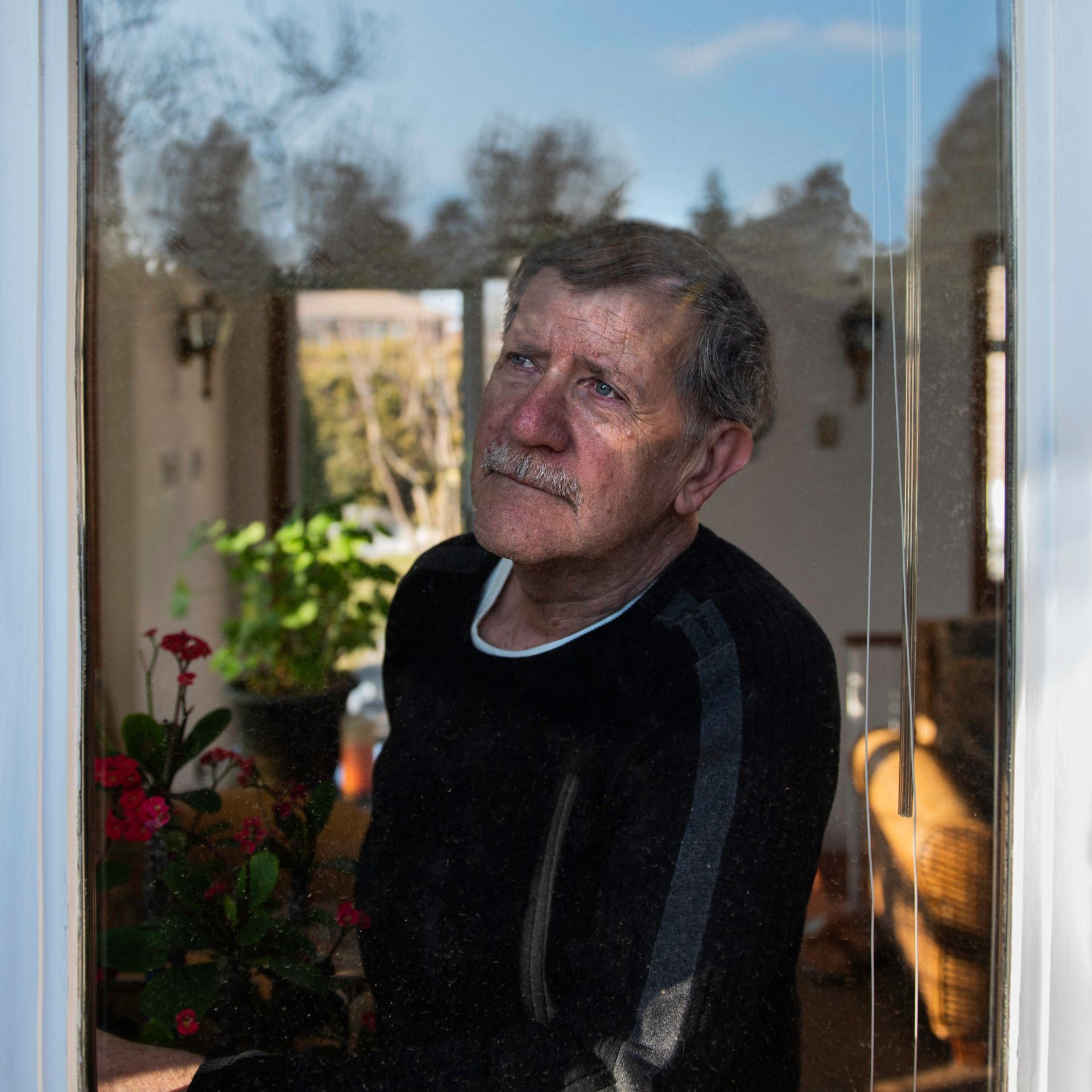 A young boy is looking out of a window.