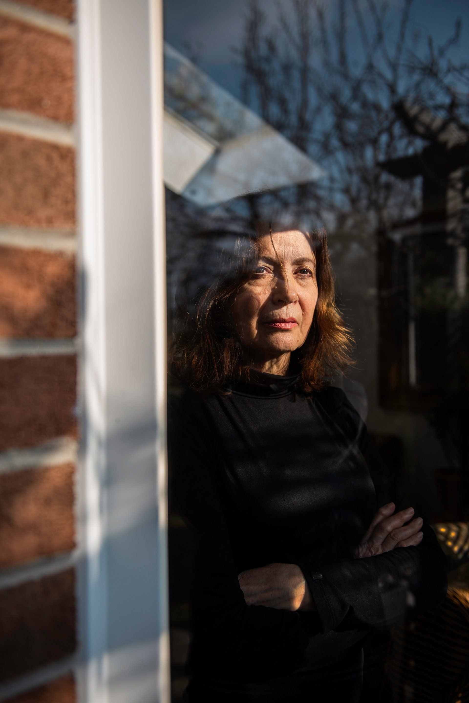 A woman is standing in front of a window.
