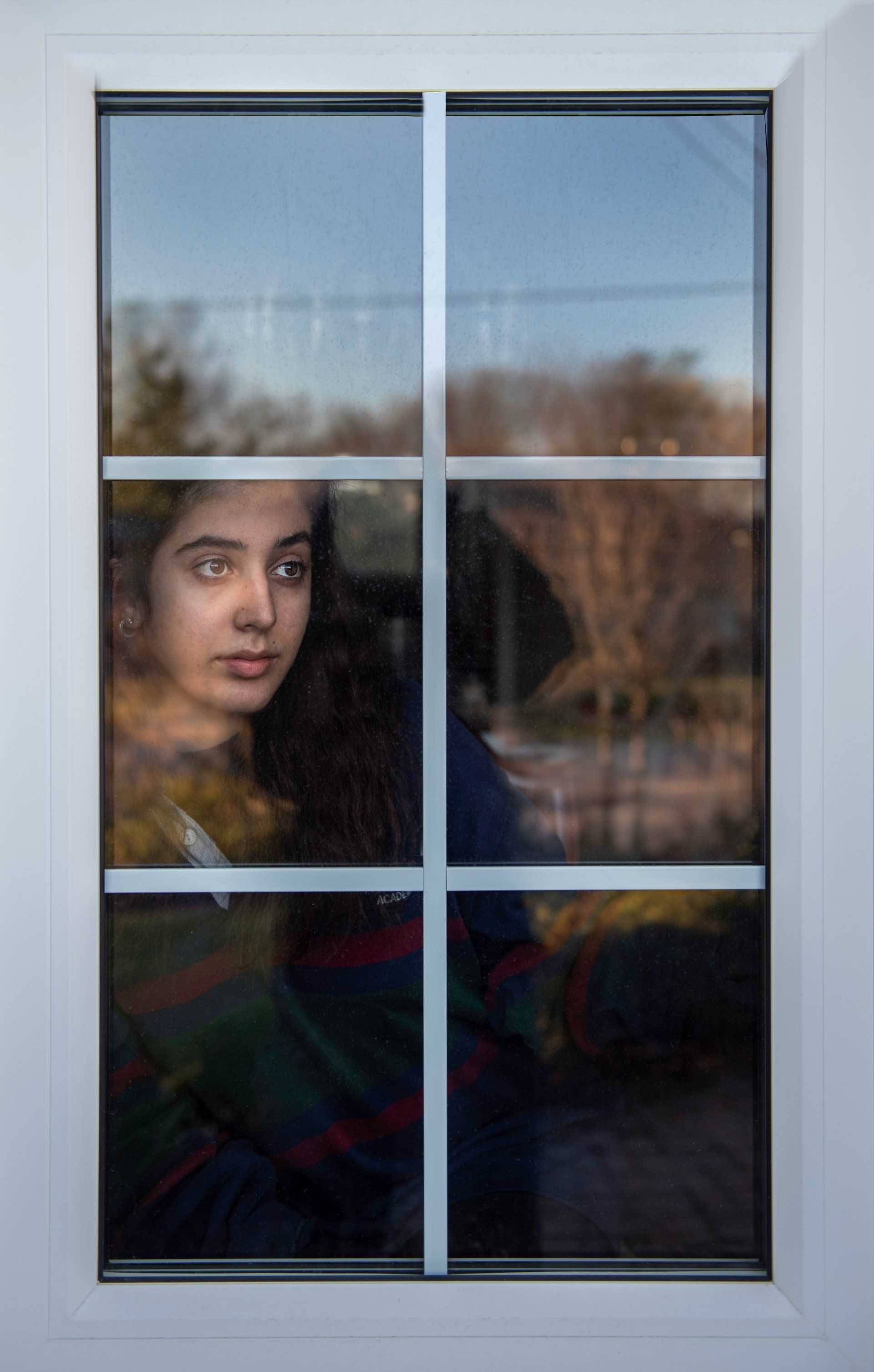 A young woman is looking out of a window.
