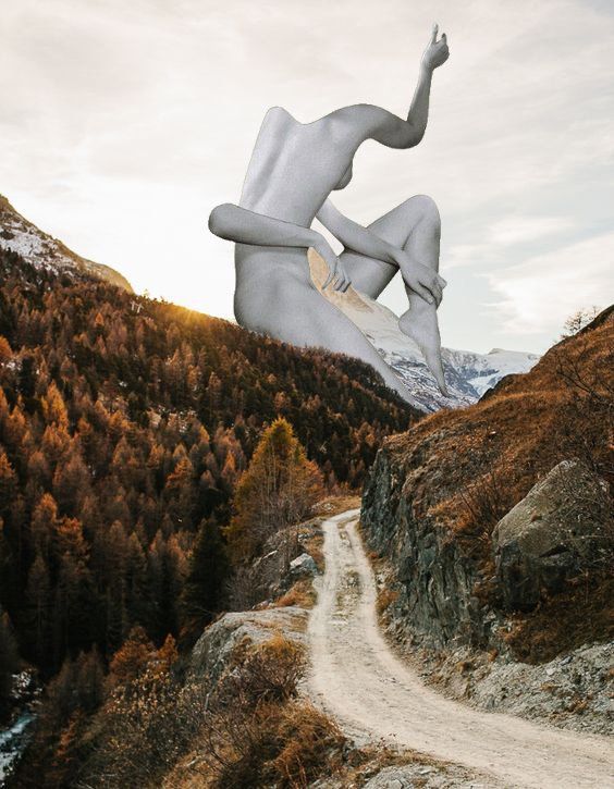 A giant, headless nude figure sits atop a mountain road, arm raised. Autumn landscape with snow-capped peaks.