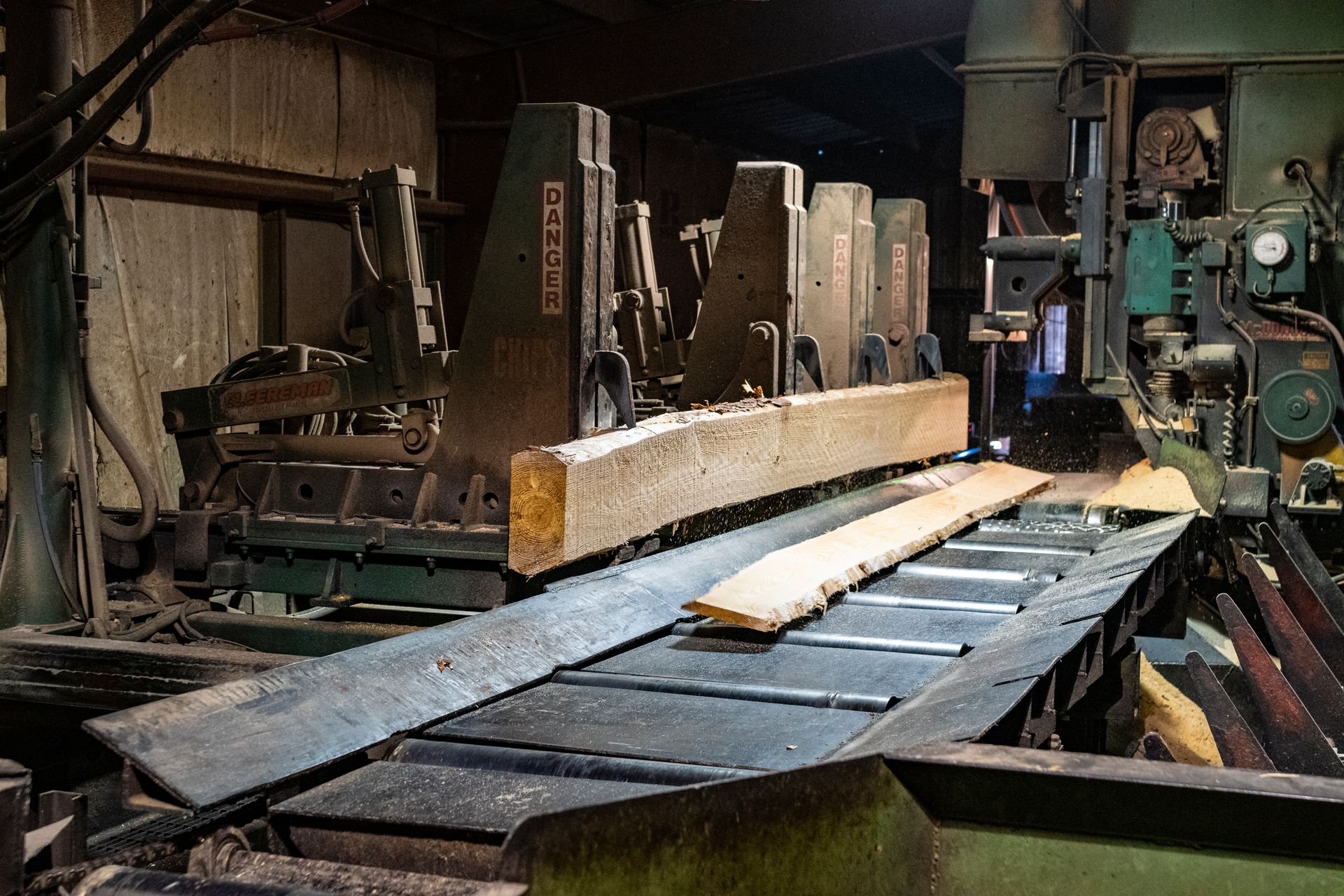 A machine is cutting a piece of wood on a conveyor belt.