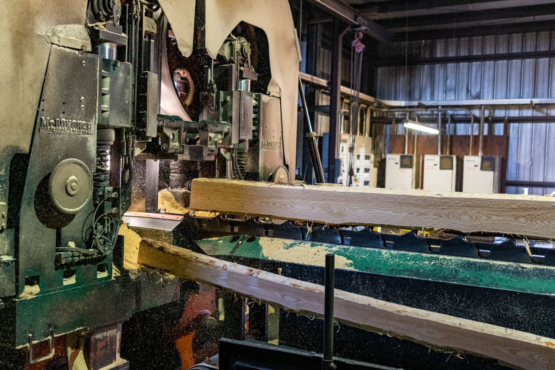 A machine is cutting a piece of wood in a factory.