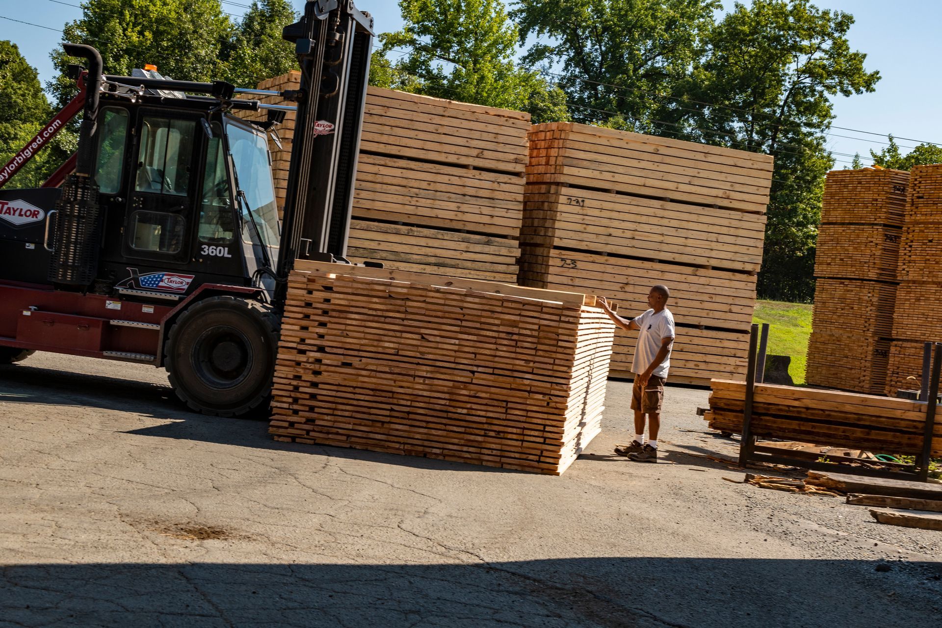 A forklift is carrying a large stack of wooden pallets